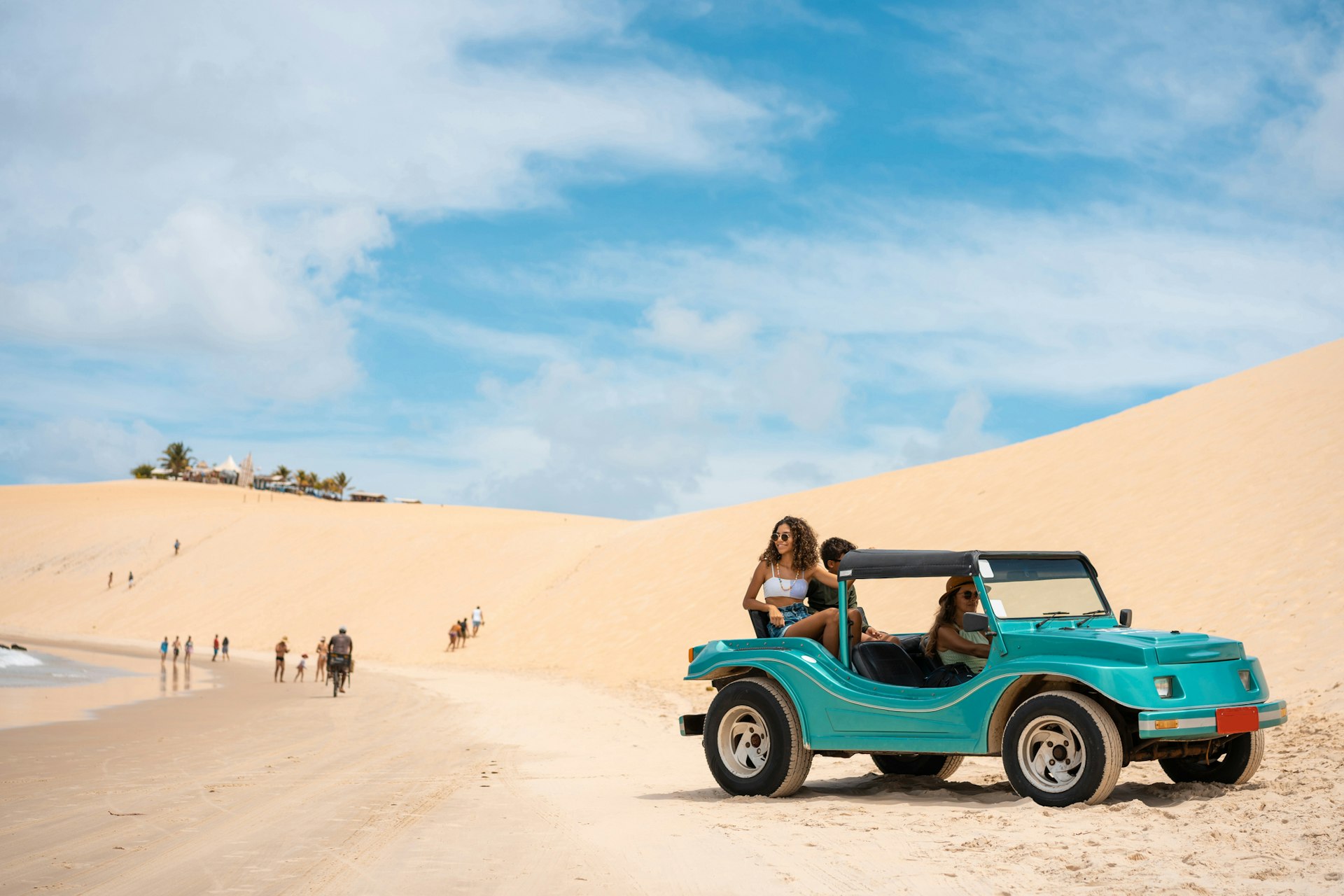 A family with two teenagers ride in a dune buggy on a sunny day