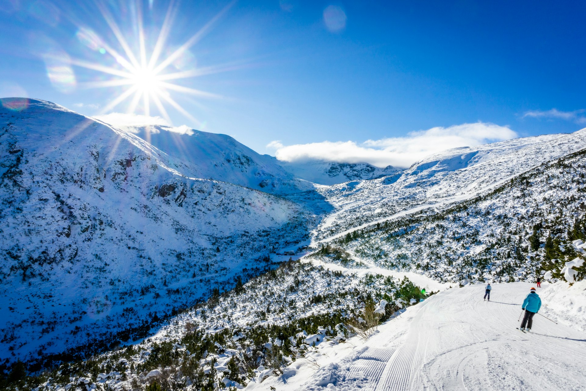 A snowy mountainscape of the valley that surrounds Borovets in Bulgaria with a skier looking out across it