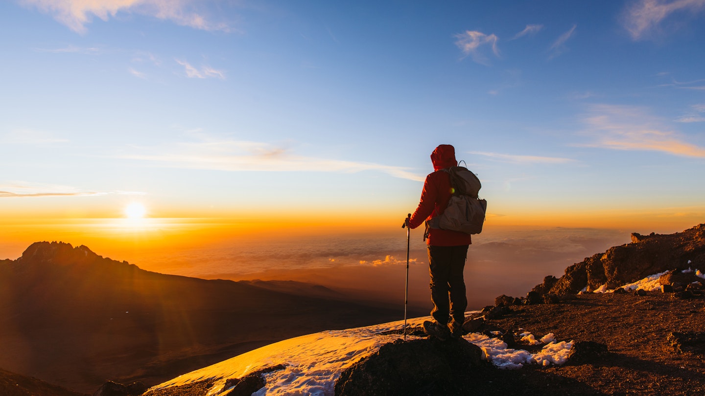 Man with backpack and hiking poles got to the top of Africa - Mount Kilimanjaro and looking at the beautiful bright sunny sunrise above the Meru mountain
1306316004