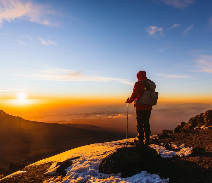 Man with backpack and hiking poles got to the top of Africa - Mount Kilimanjaro and looking at the beautiful bright sunny sunrise above the Meru mountain
1306316004