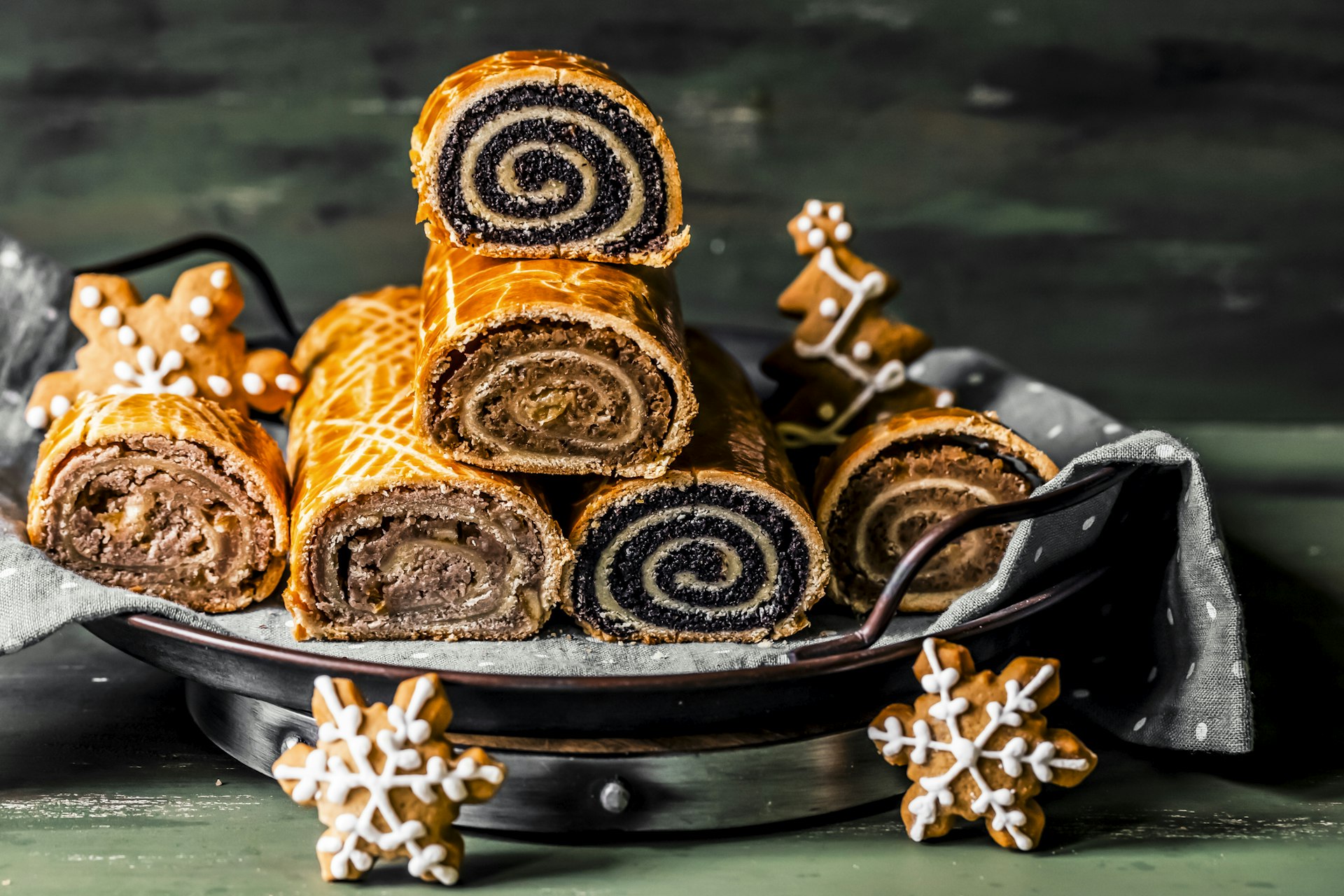 A pile of Hungarian beigli cake cut to show the swirling center and piled high surrounded by Christmas decorations