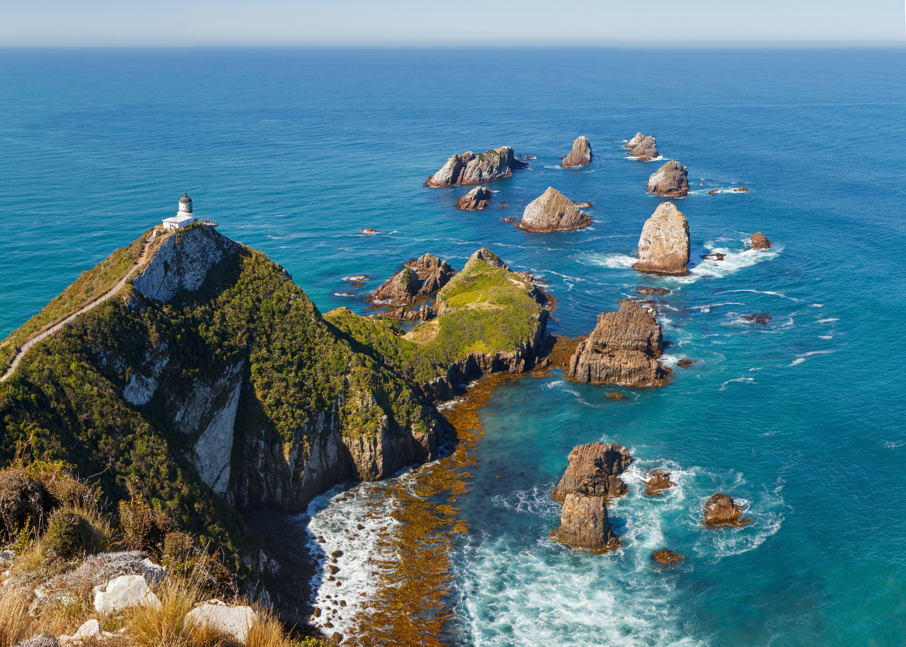 A rocky bluff in New Zealand with a lighthouse overlooking the ocean