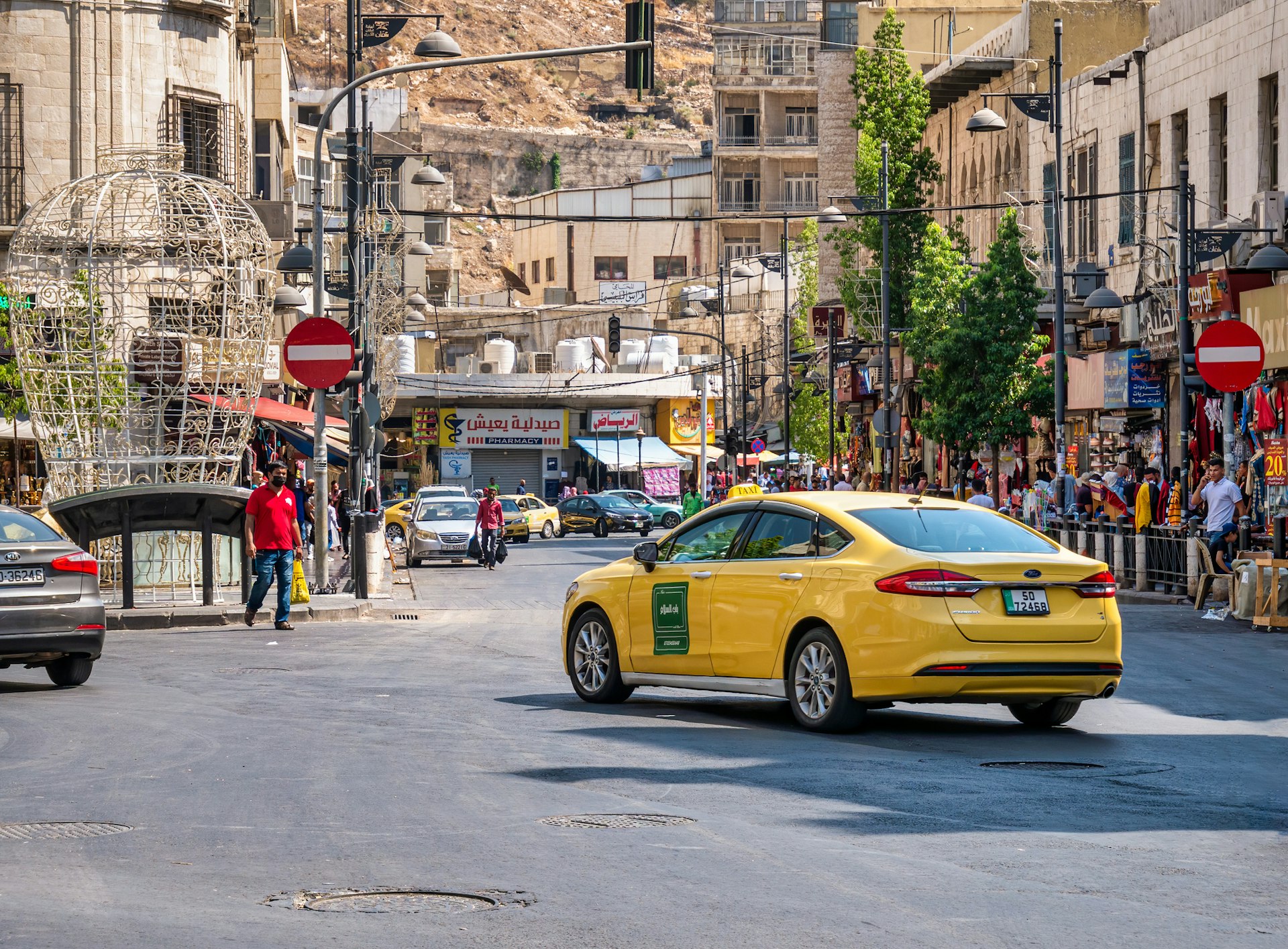 A yellow taxi driving along a busy street in Amman, Jordan