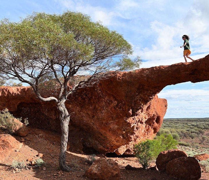 A young girl crossing over London Bridge arch near Sandstone in the outback of Western Australia.