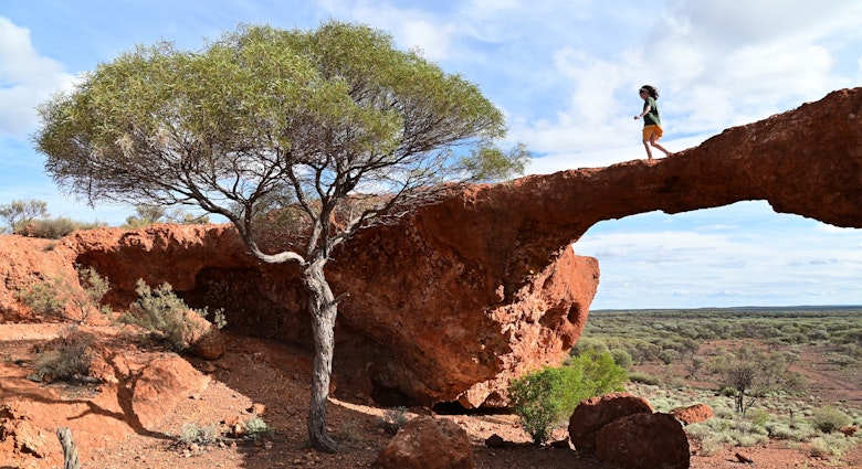 A young girl crossing over London Bridge arch near Sandstone in the outback of Western Australia.
