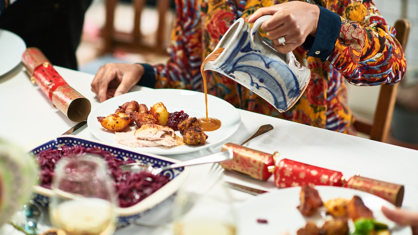 Woman holding jog and pouring gravy onto traditional Christmas dinner, roast meat and vegetables on plate, sauce, preparation, temptation, healthy eating
1393670282