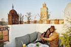 Medium wide shot of smiling couple enjoying sunset dinner at rooftop restaurant in the Medina of Marrakech while on vacation
1463518558