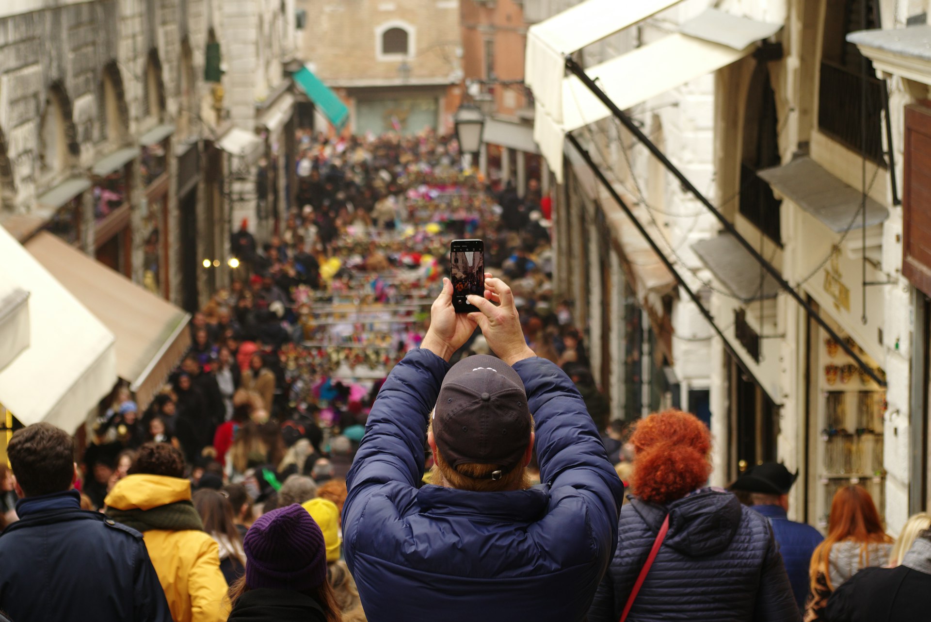 A man takes a picture of a crowded Venice street
