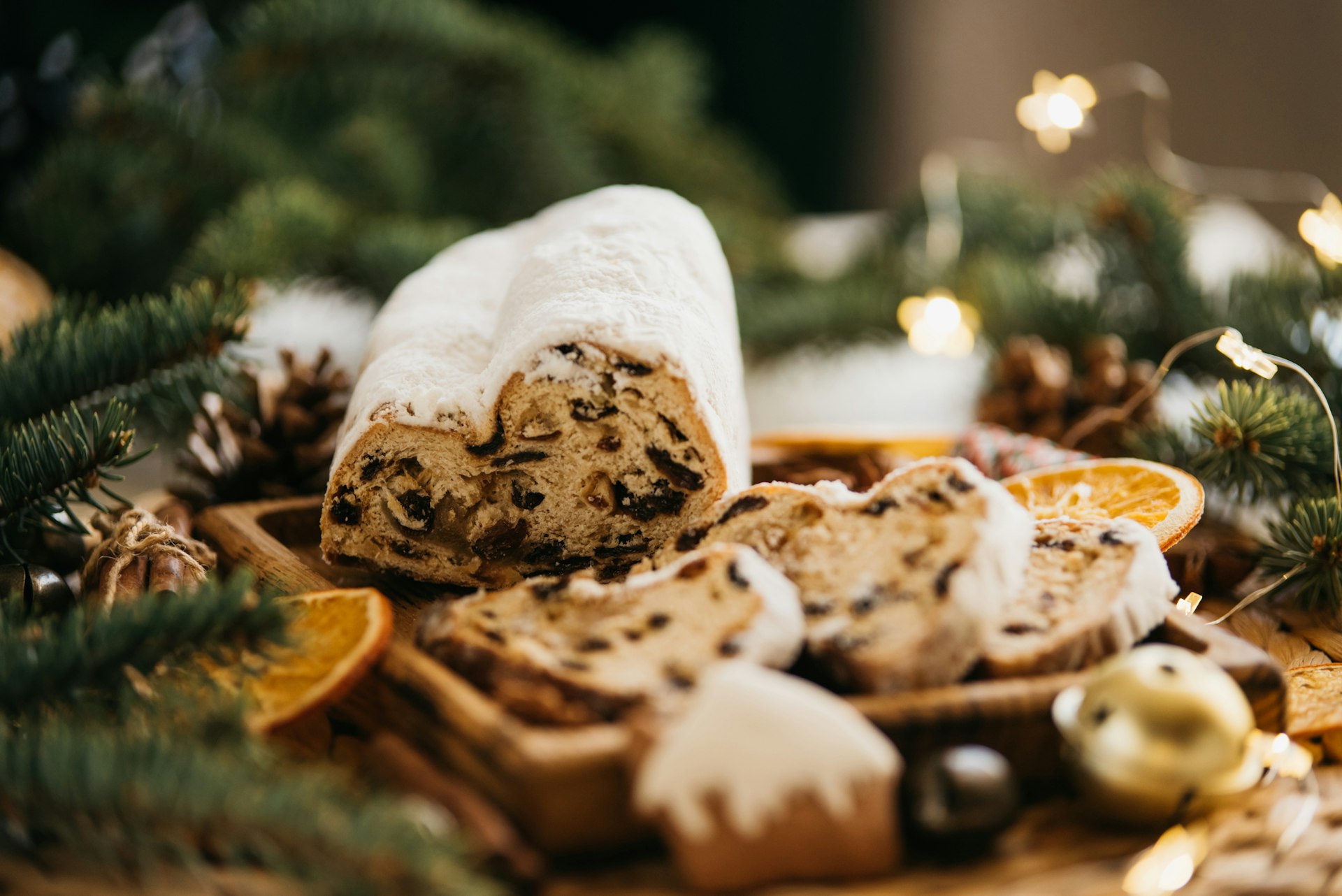 Christmas stollen on wooden background. Traditional Christmas German dessert cut into pieces. Cake with nuts, raisins with marzipan and dried fruit on cutting board. baking for Xmas