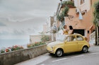 Two beautiful young woman inside a small, vintage yellow car. The top remains open. They stand up in the vehicle, through the sunroof and take photos of each other. We can see Italy's famous view of Positano in the background. Depicts a scene of experiential travel, suggesting renting a car, travel tours, European road trips and nostalgia.
1492413341