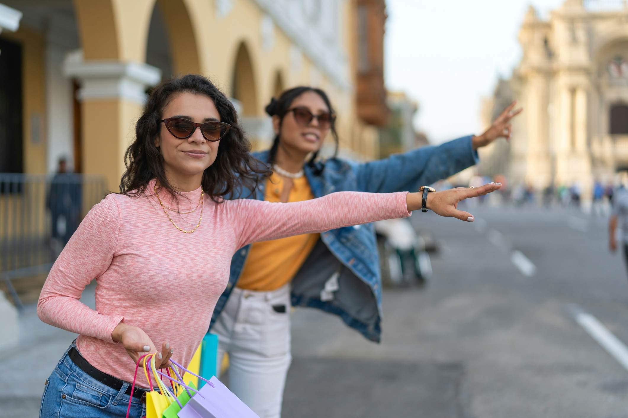 Friends looking for a cab carrying their gift bags after a day of shopping, wearing sunglasses.
1662548844