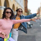 Friends looking for a cab carrying their gift bags after a day of shopping, wearing sunglasses.
1662548844