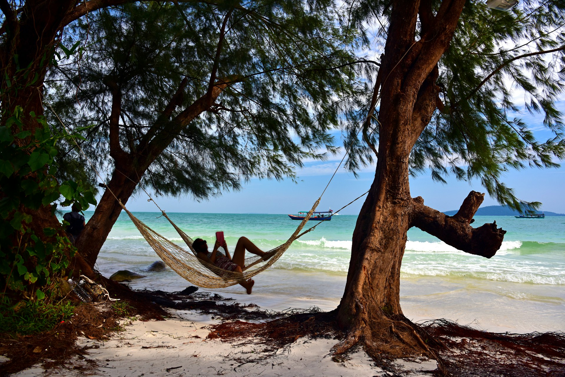 A woman lounges in a hammock in the shade on the shores of Koh Rong