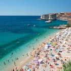 View of a packed Dubrovnik Beach with the Old Town Harbour in the background.
519657843