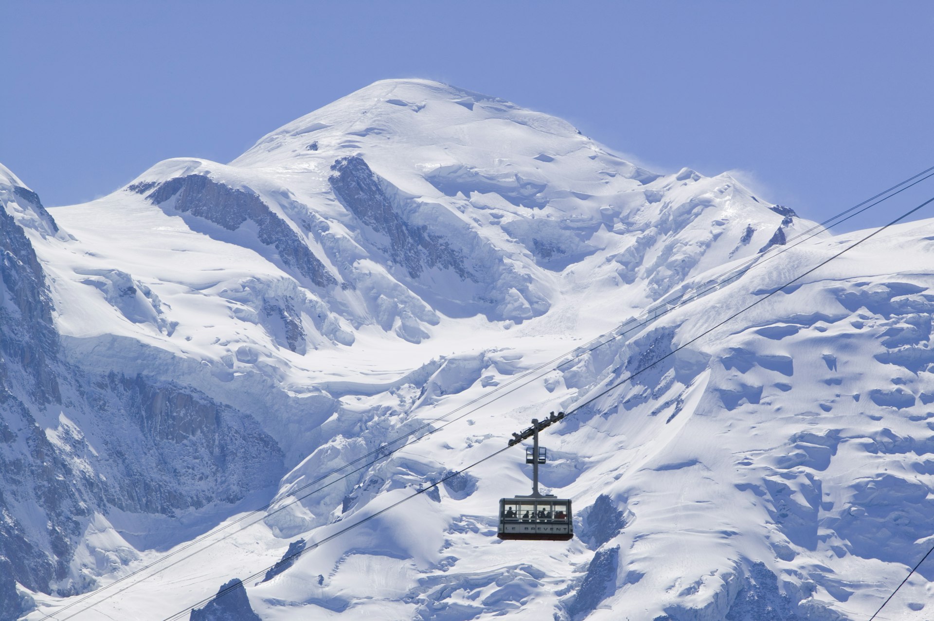 A cable car passes in front of the snowy peak of Mt Blanc