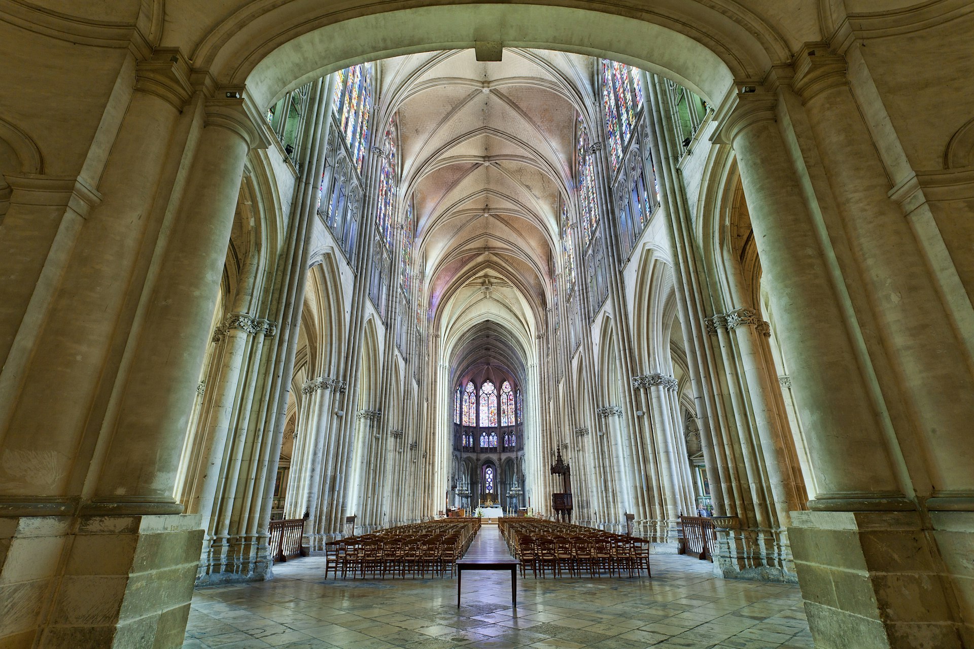 A huge columned church nave glowing with the color of the sun shining through its stained-glass windows