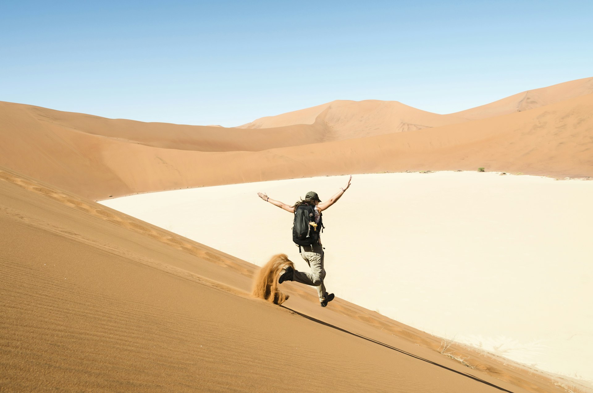 A woman runs down a sand dune near Deadvlei, Namib Desert, Namibia