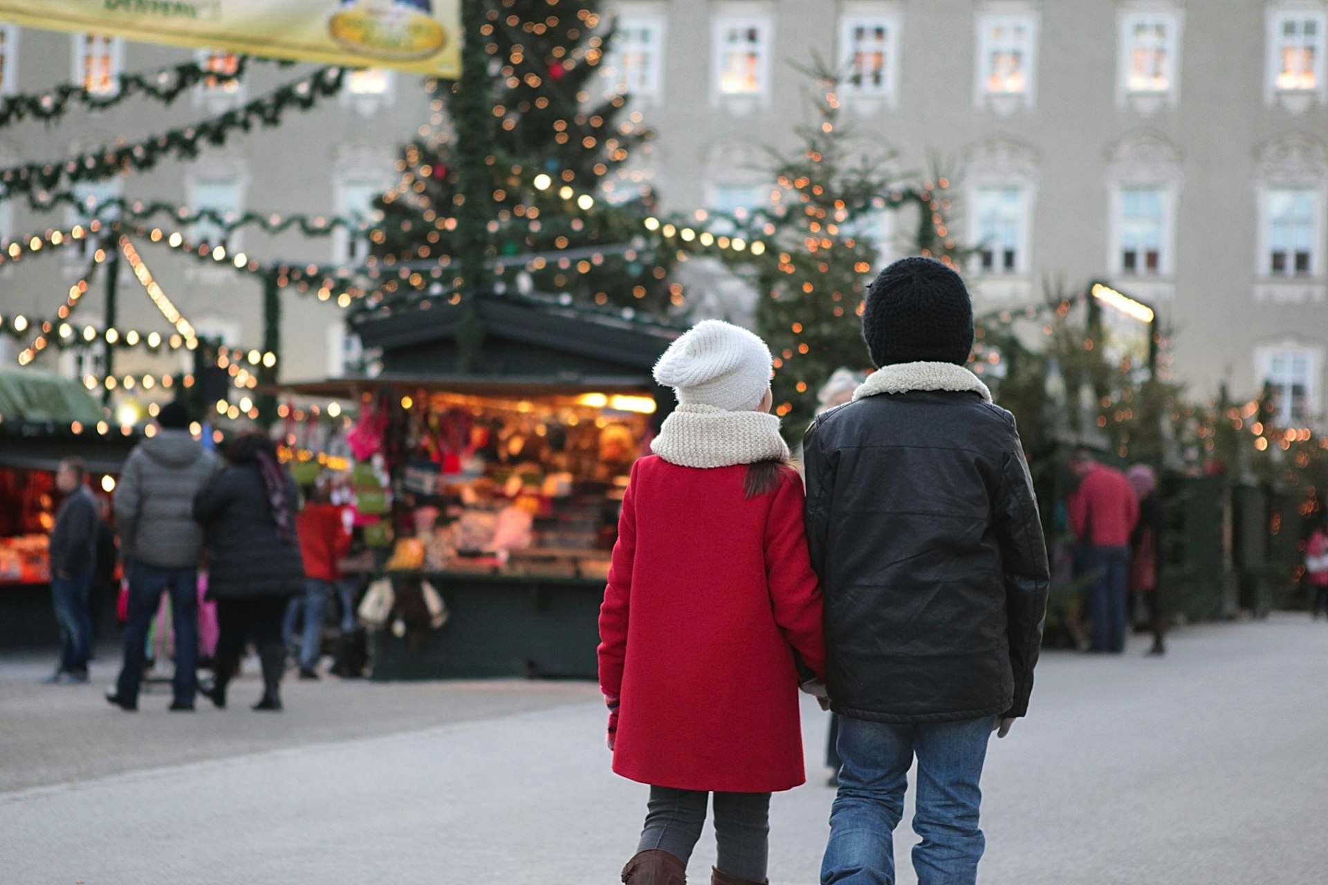 Young boy and girl, siblings, are walking hand in hand towards the Christmas market at Schloss Hellbrunn, Austria