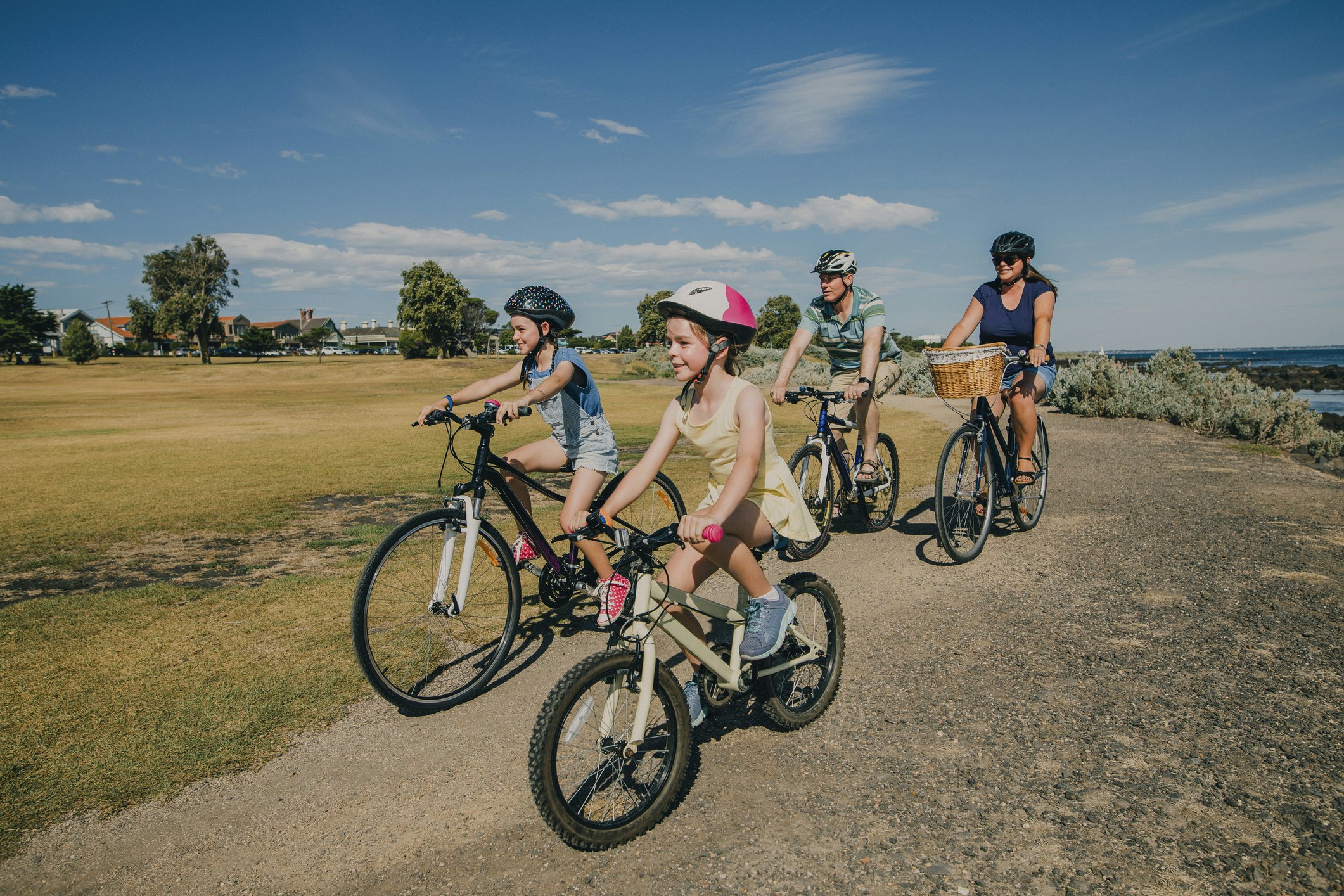 Two parents cycling with their two kids through a park in Melbourne