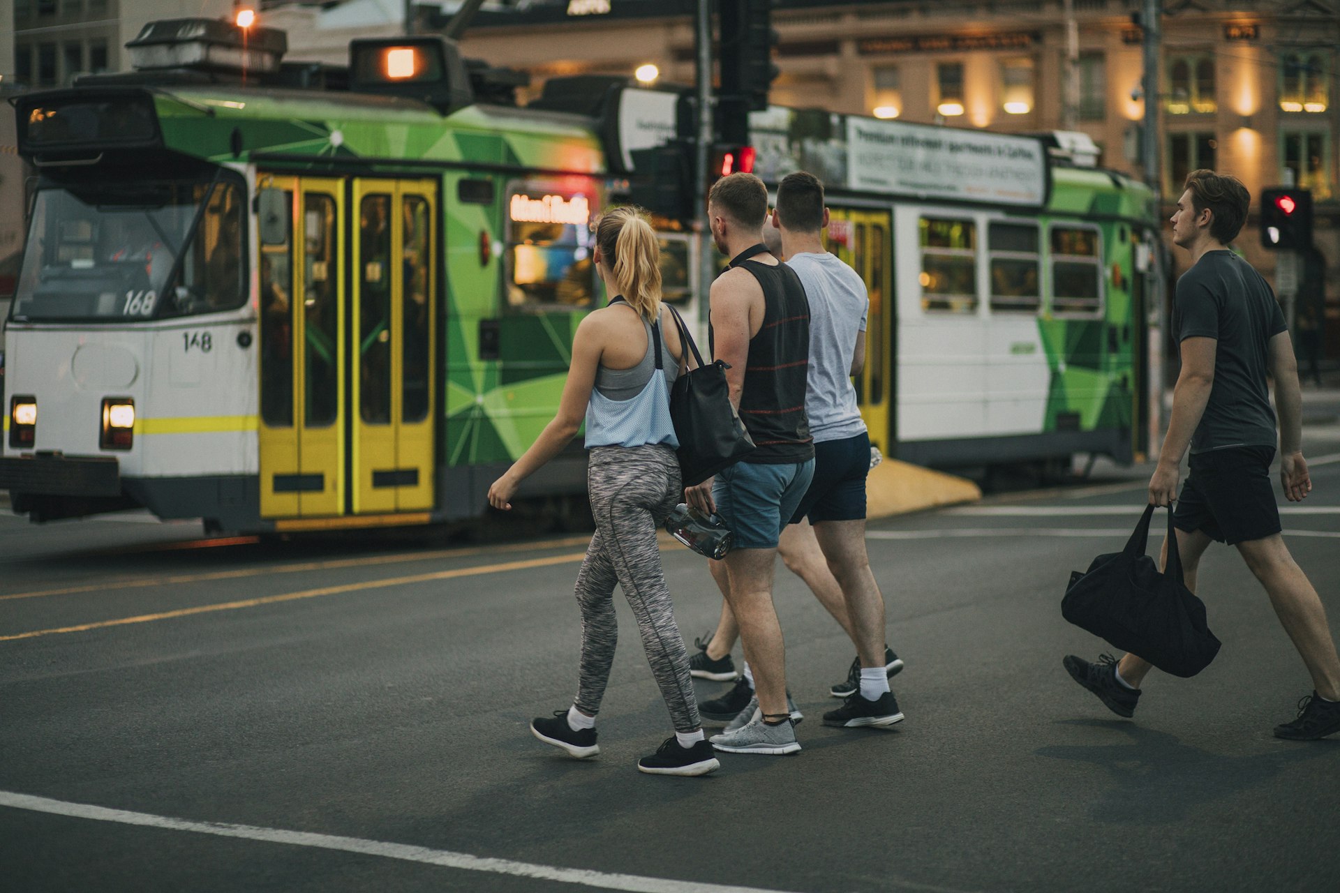 A group of friends crossing the street next to a tram in Melbourne