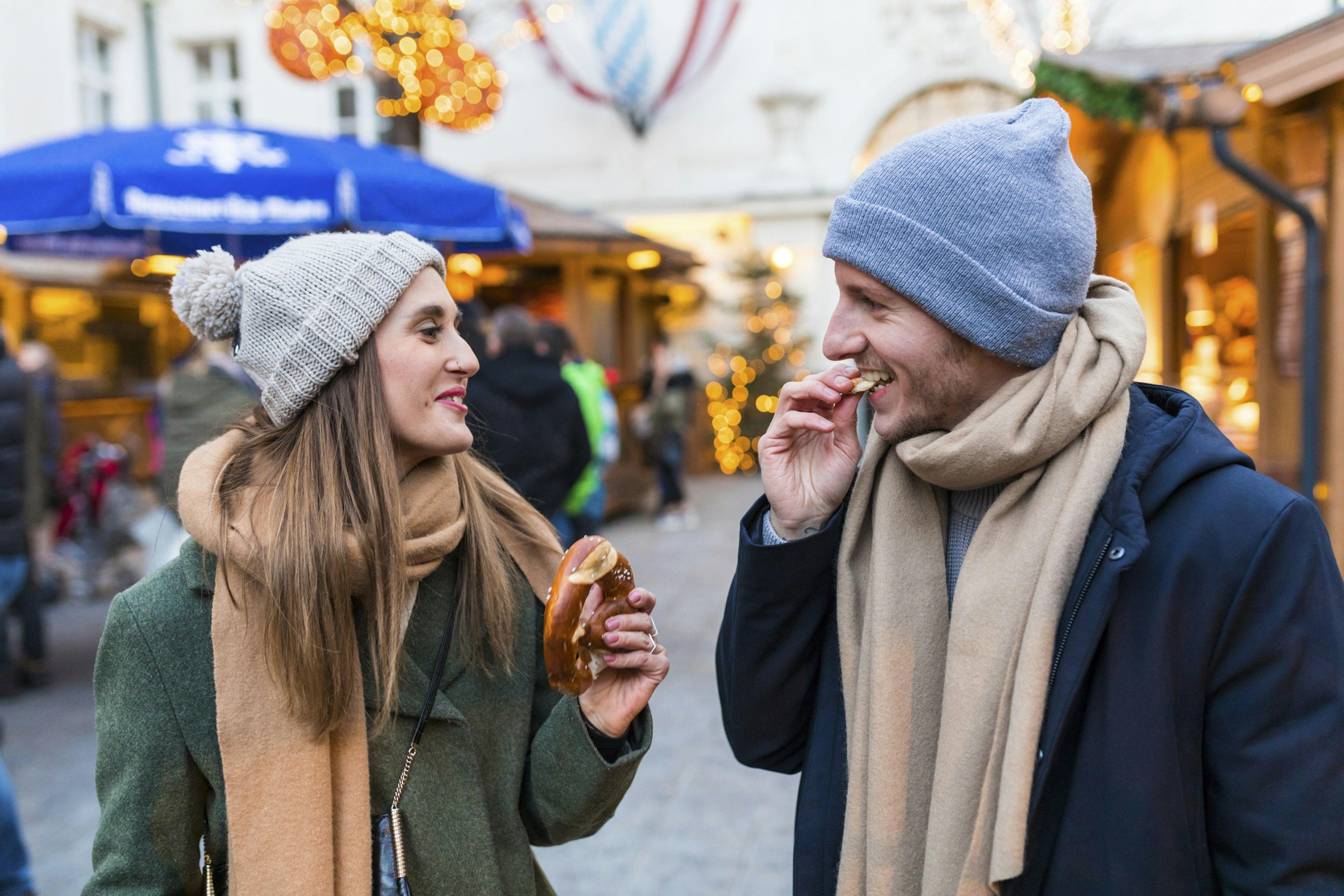 A man and a woman eat a pretzal at Innsbruck Christmas market in Austria