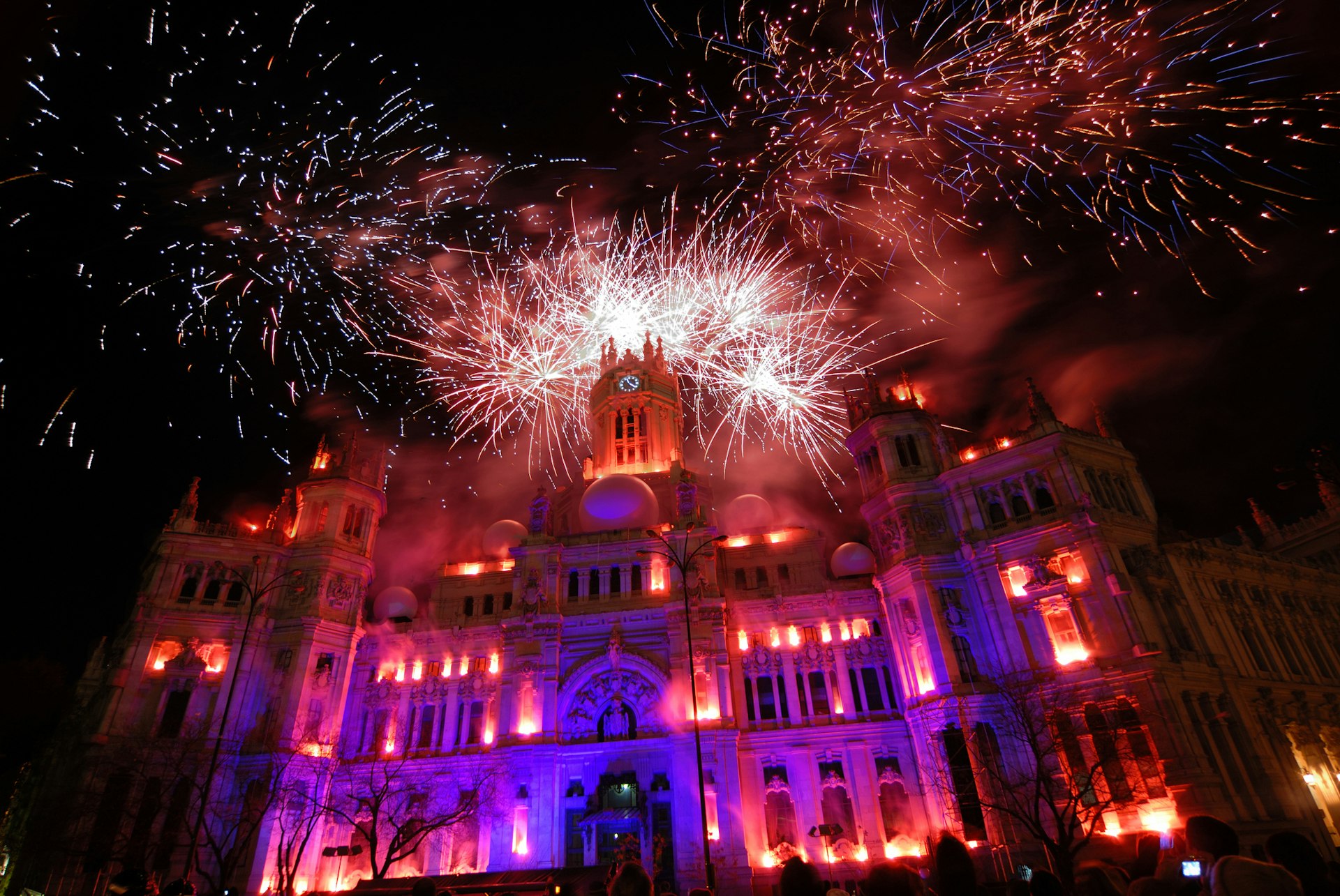 Fireworks explode in red and yellow over Madrid's city hall as part of New Year celebrations