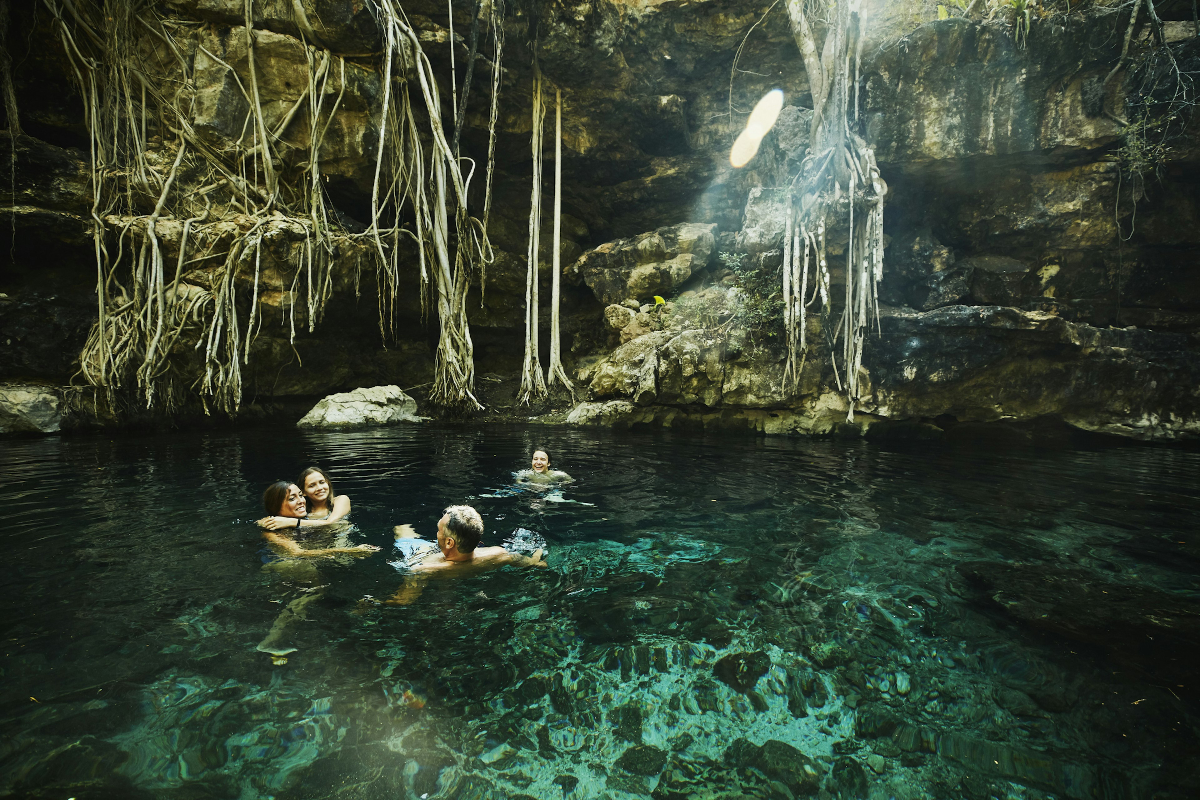 A family with two children swim together in a freshwater pool that's formed in a cave system