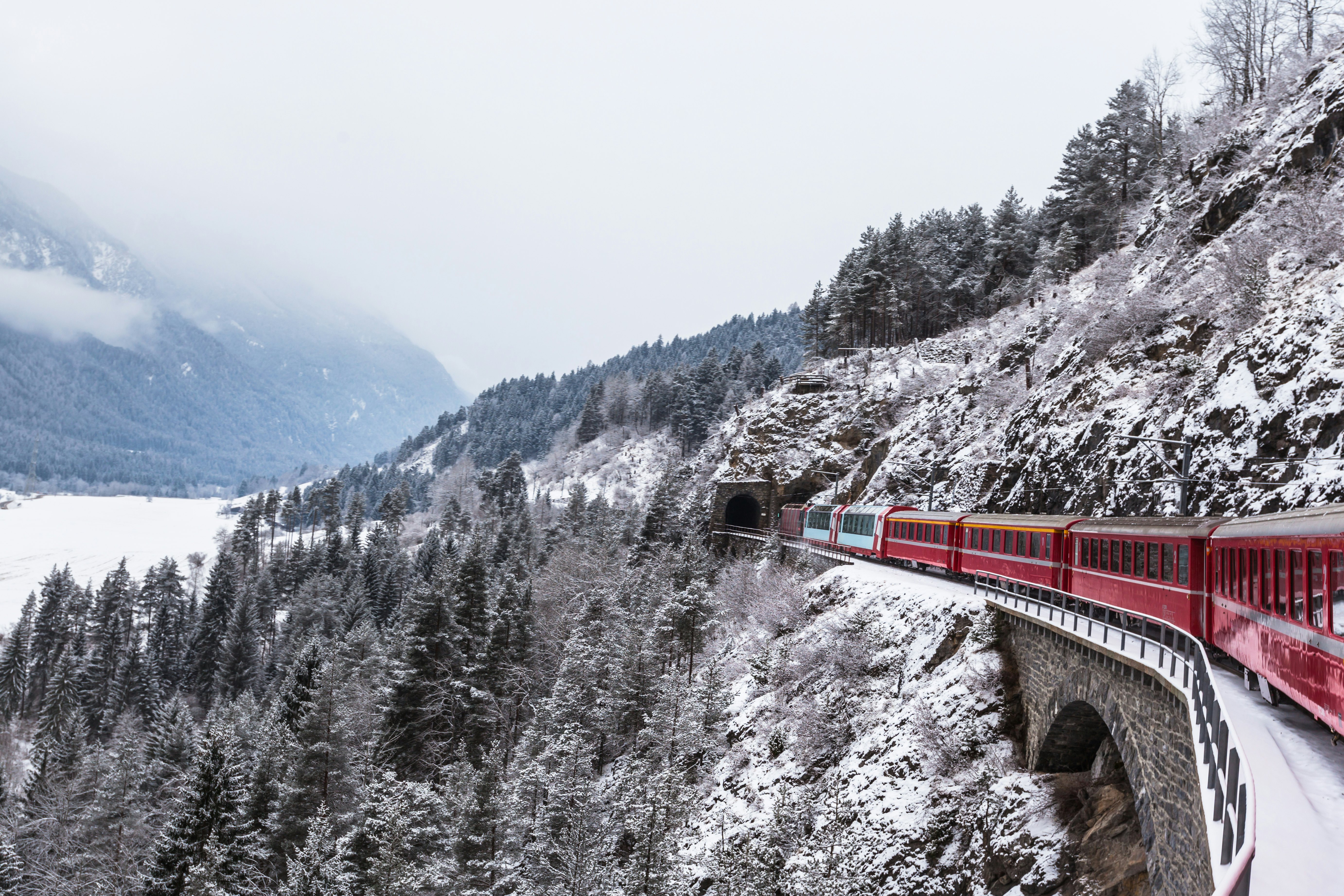 A train enters a tunnel in a snowy landscape in Switzerland.