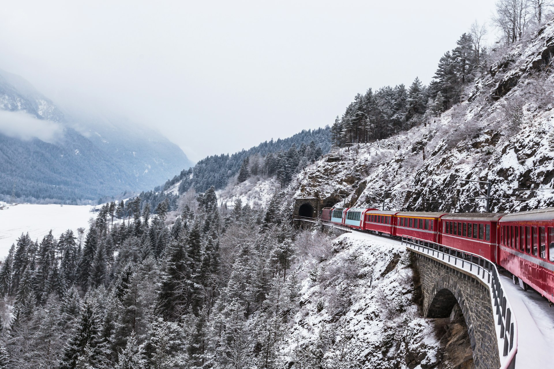 A train enters a tunnel in a snowy landscape in Switzerland. 