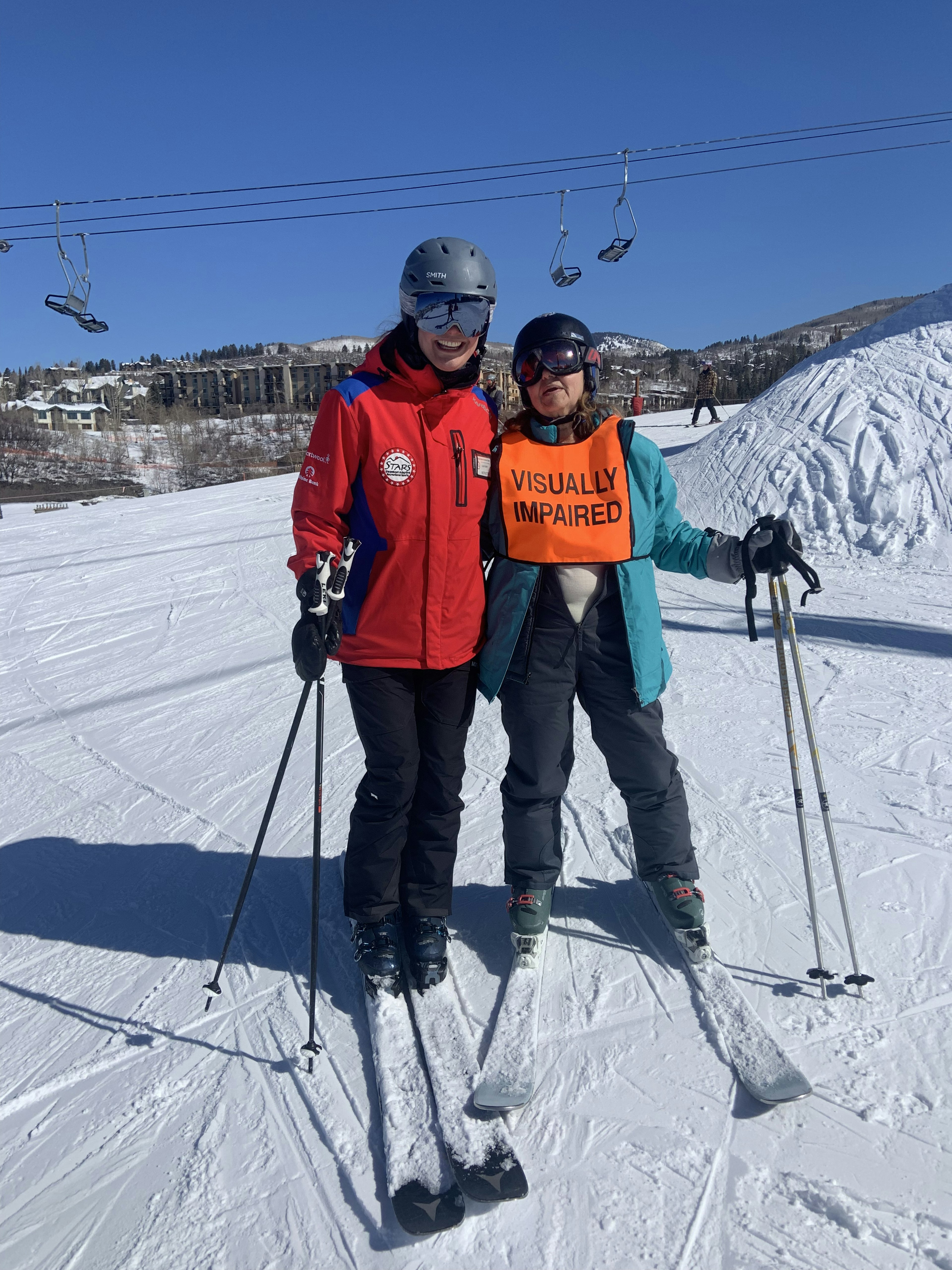 A ski instructor guides a skier down a slope