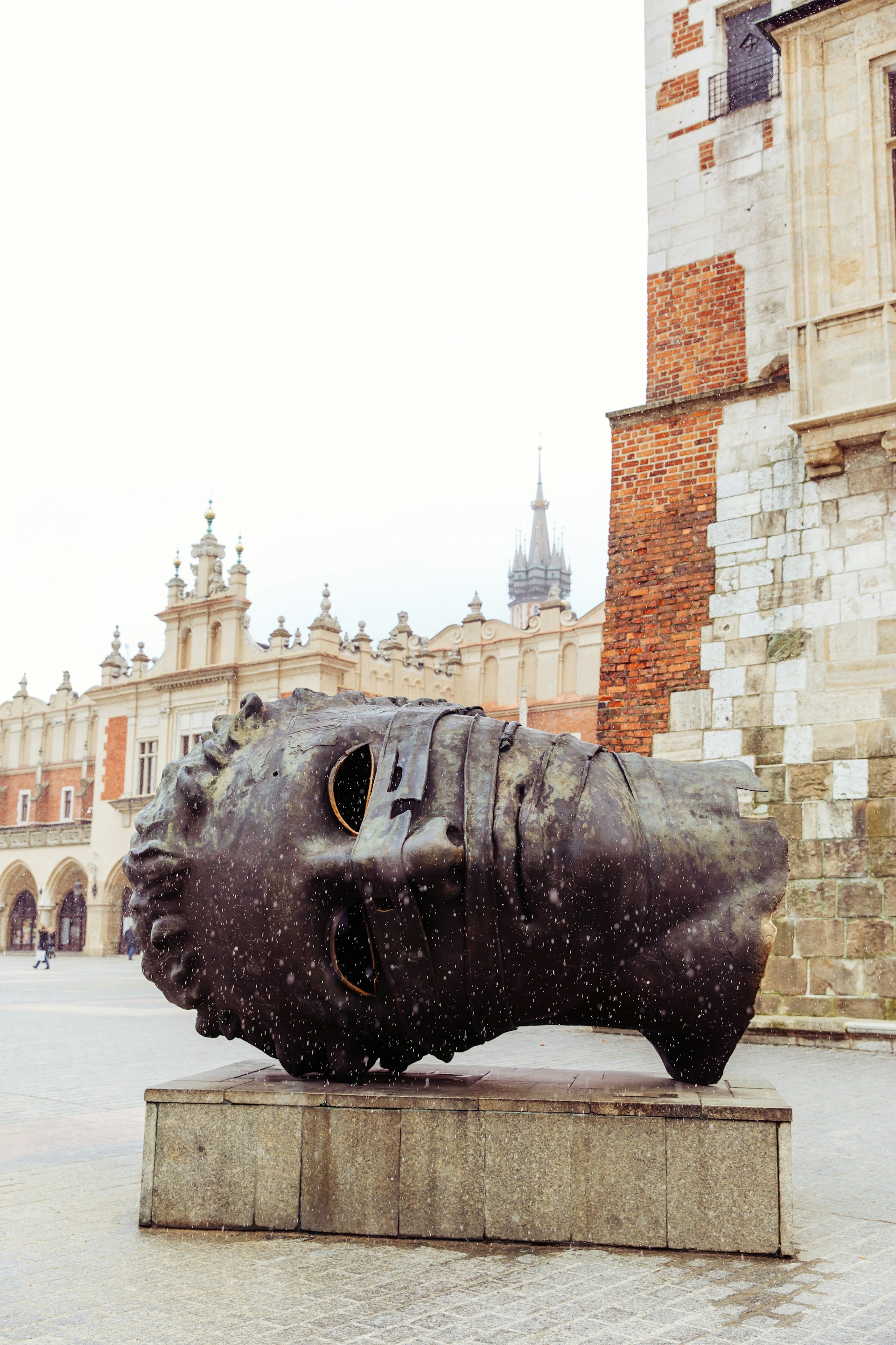 'The Head' sculpture in Market Square, Krakow with pedestrians in the background