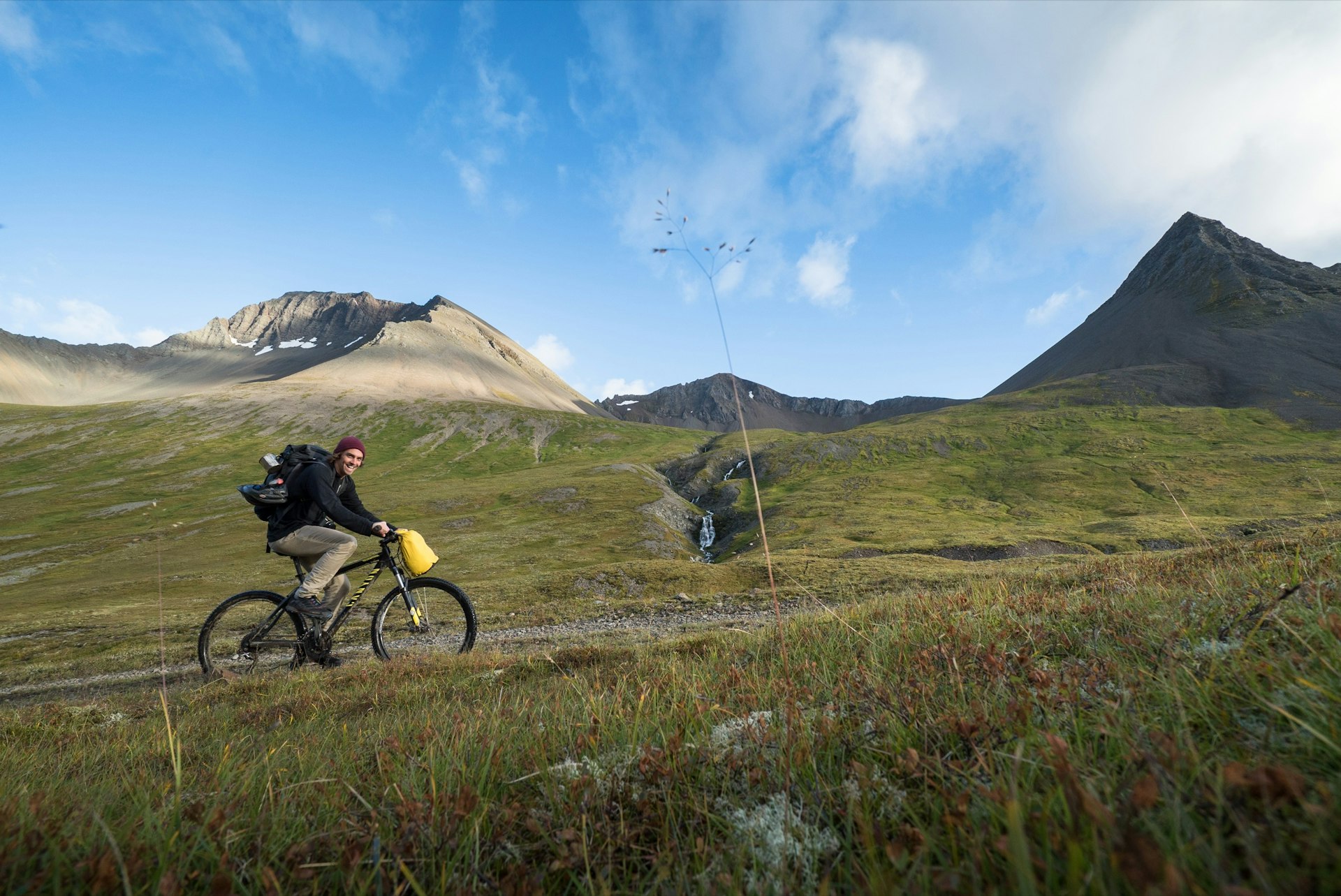 A man is cycling up Kirkjubolsdalur, on the path to Kaldbakur mountain, Westfjord