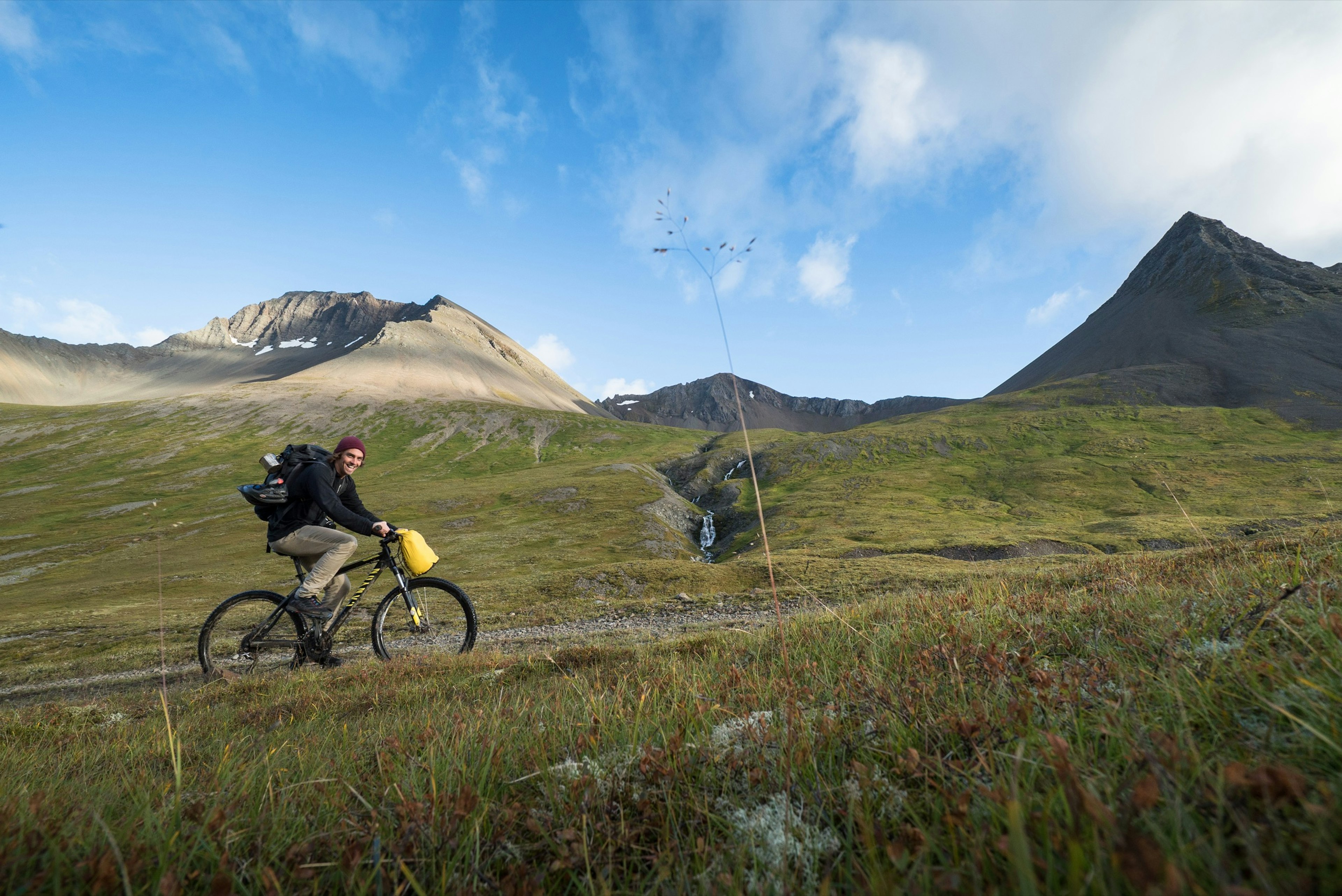 A man is cycling up Kirkjubolsdalur, on the path to Kaldbakur mountain, Westfjord