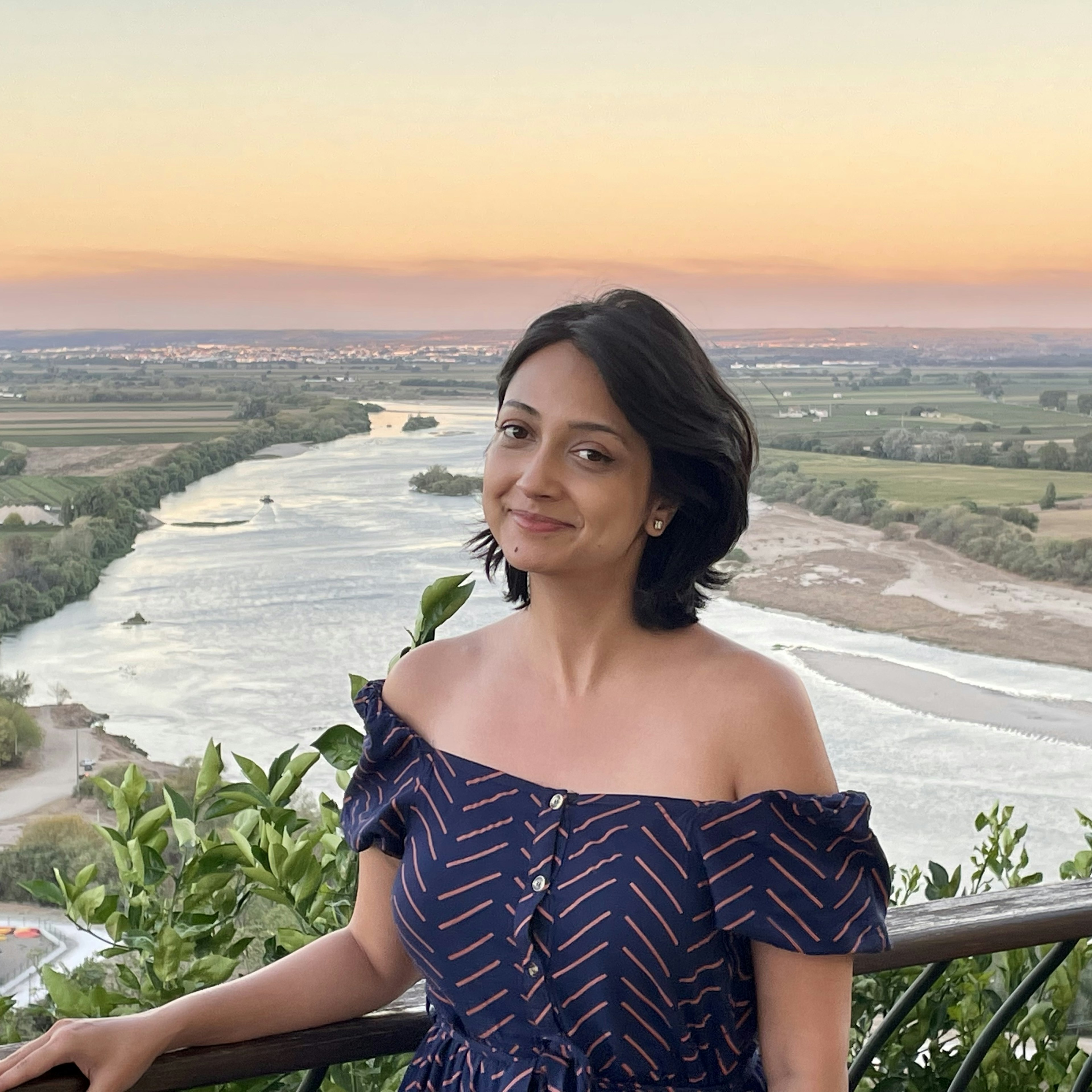 Akanksha Singh in Portugal, standing with the Tagus River behind her.