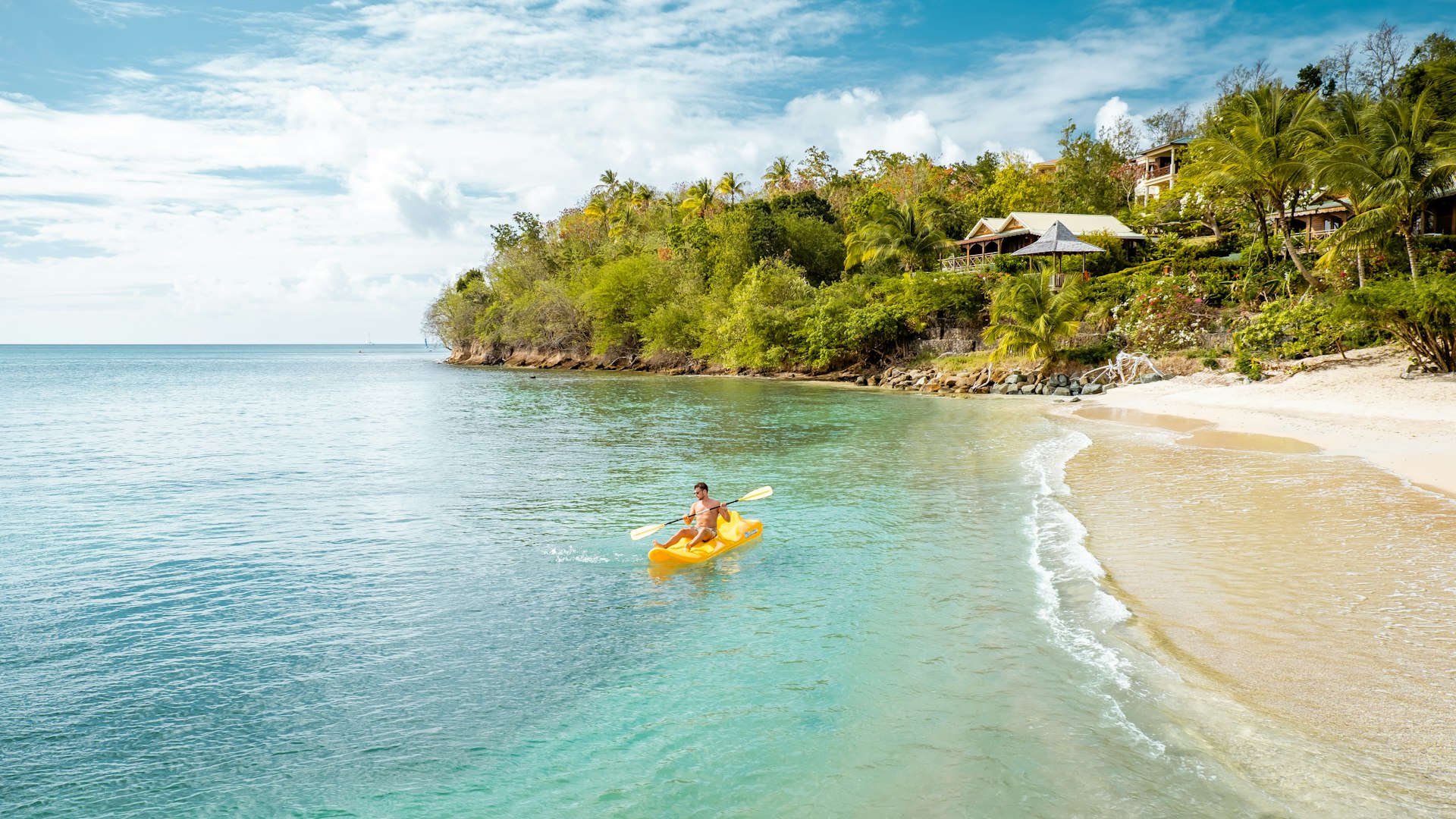 A man on yellow kayak on a tropical beach St Lucia Caribbean