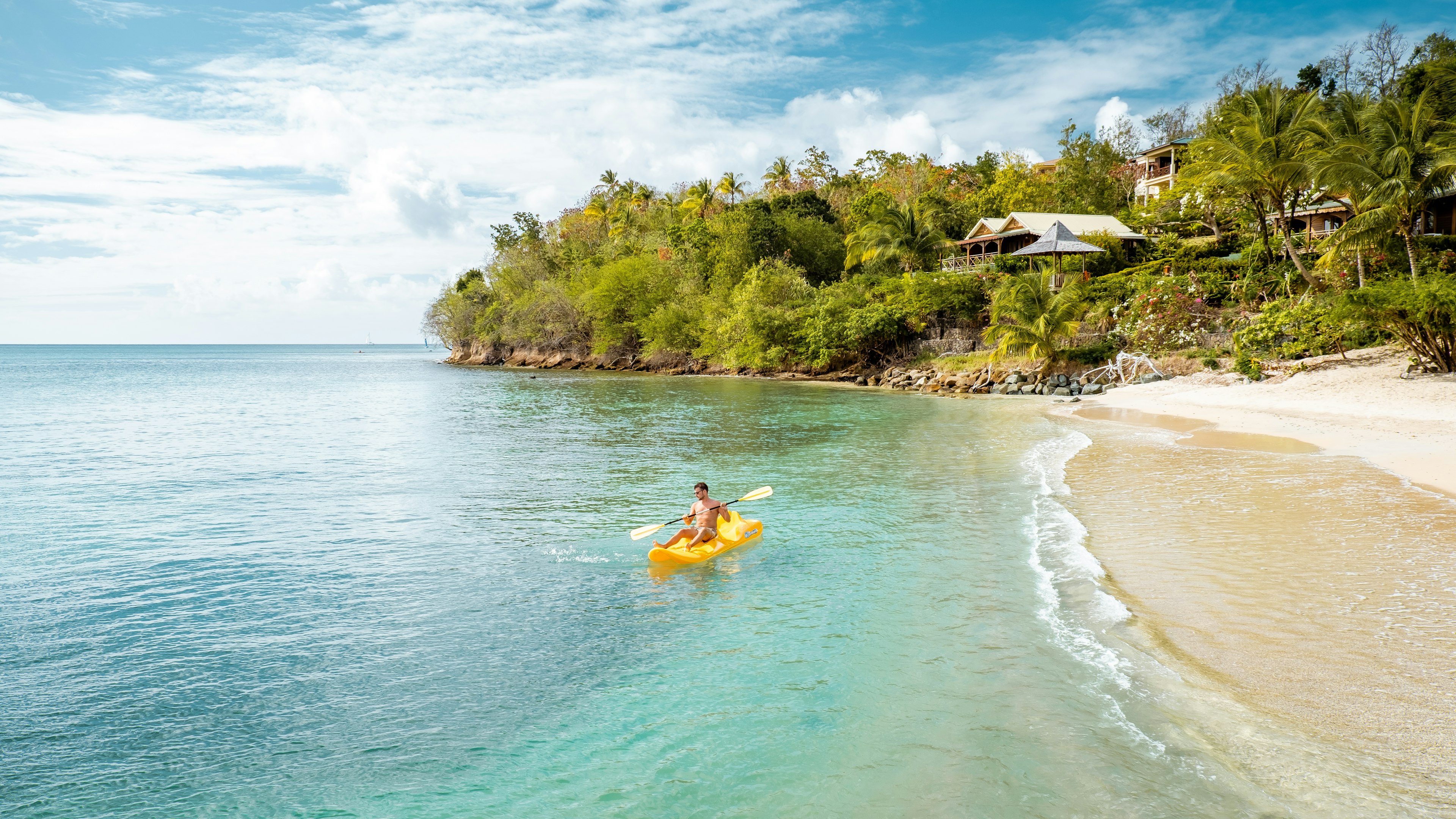 A man on yellow kayak on a tropical beach St Lucia Caribbean