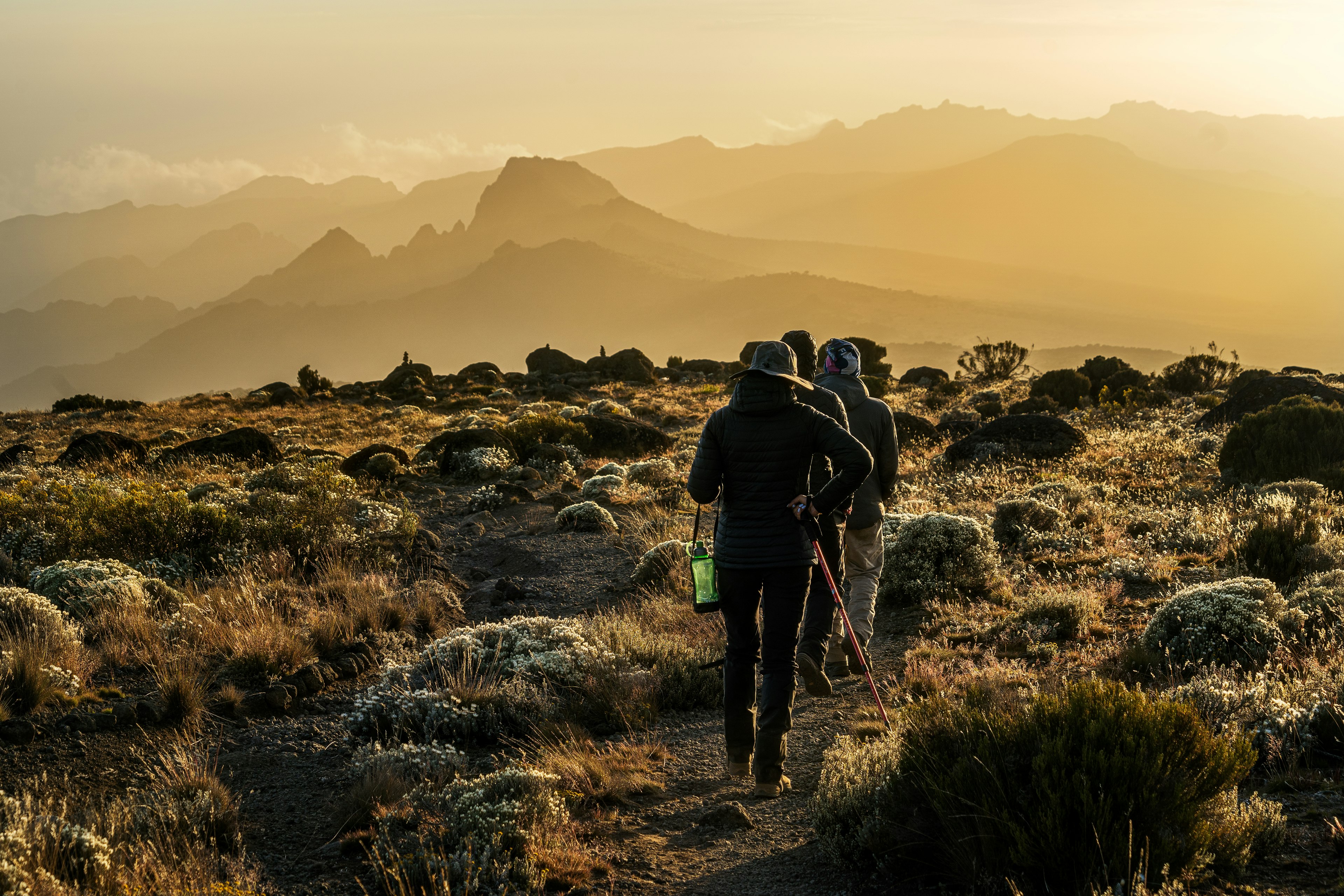 A group of people hike along a rocky ridge at sunset in Tanzania