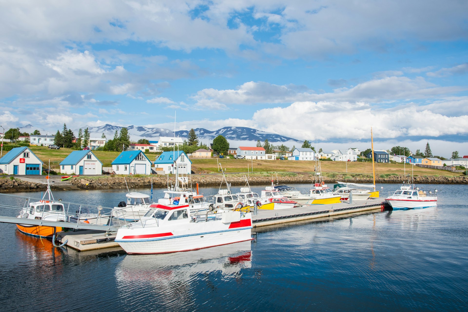 Summer day in village of Hrisey in North Iceland with boats on the water and brightly-colored homes in the background