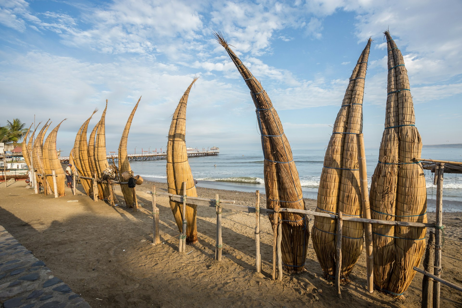 Reed boats stand on end along the sand in Huanchaco, Peru