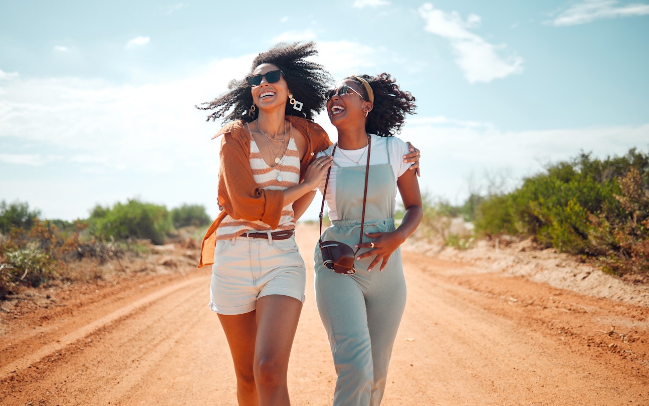 Two women walking along a path in a park in Kenya while laughing together