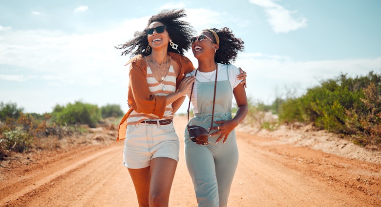 Two women walking along a path in a park in Kenya while laughing together