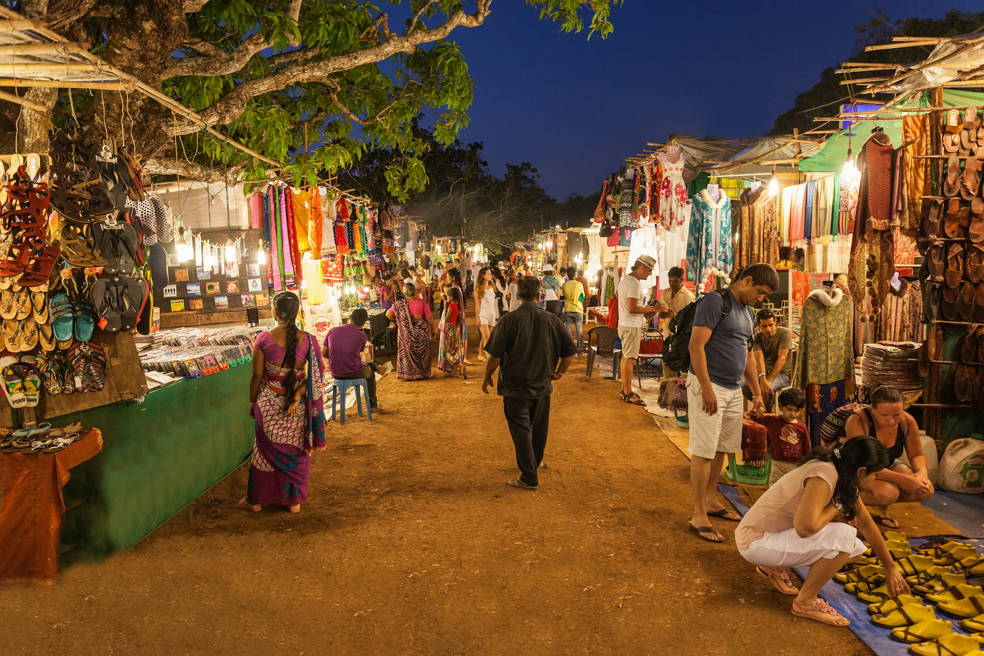 Several shoppers look at the clothes, shoes and textiles on display in the stalls at Goa Night Market, Goa, India