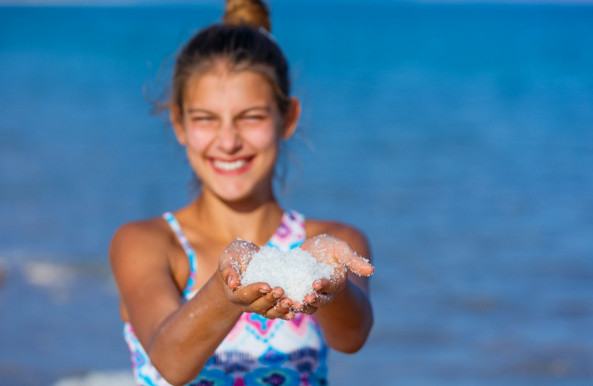 A teen girl holds a handful of salt at the Dead Sea