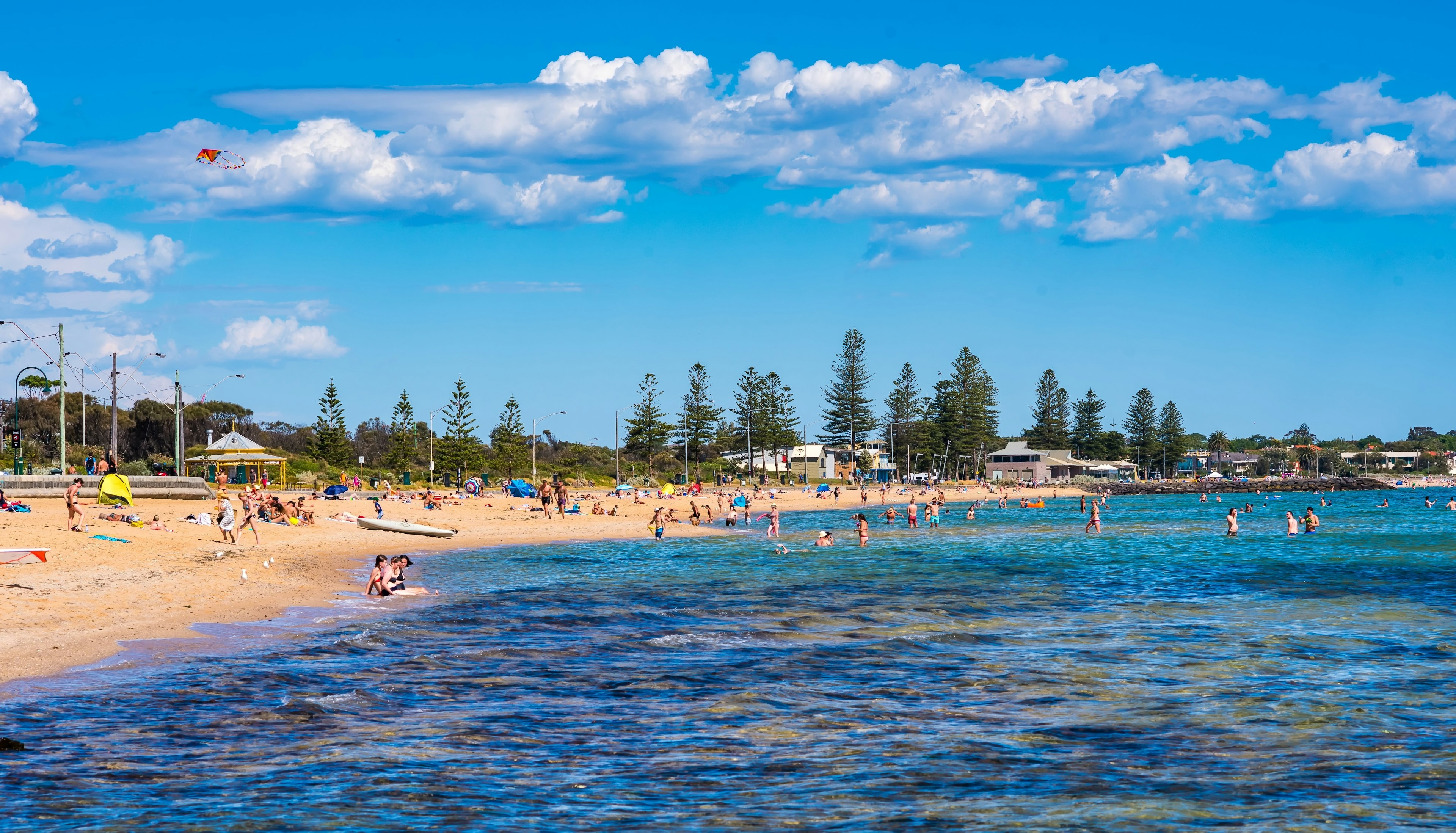 A beach with swimmers entering the water and sunbathers on the sand