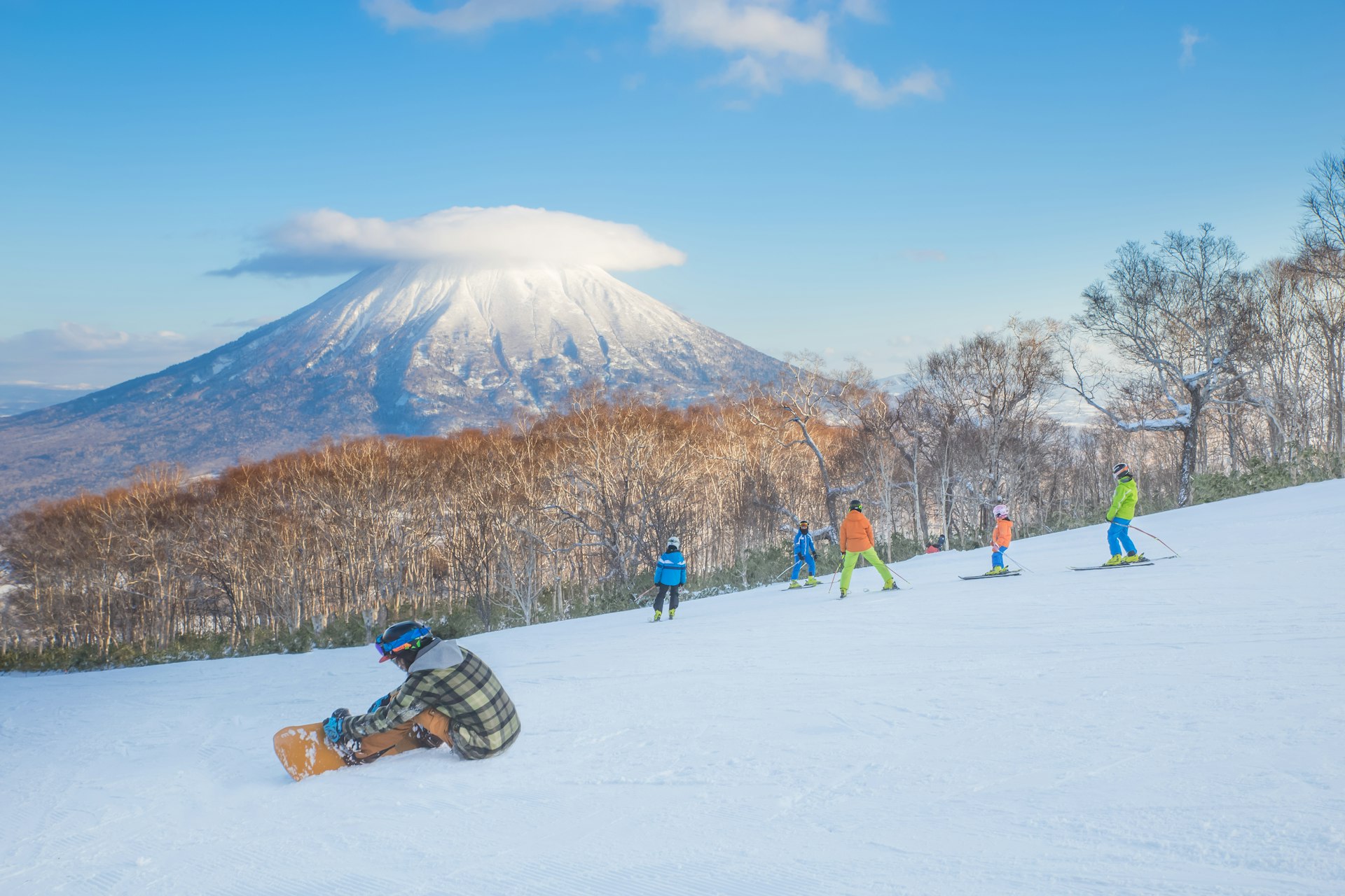 People skiing on the snow slope with Mt Yōtei in the background in Niseko Ski area, Hokkaidō, Japan