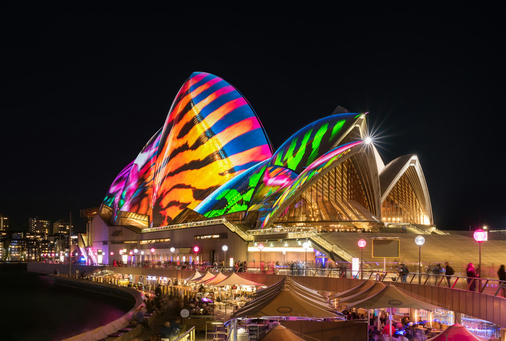 The iconic Opera House in Sydney is used as a projector screen, covered with colorful lights and images