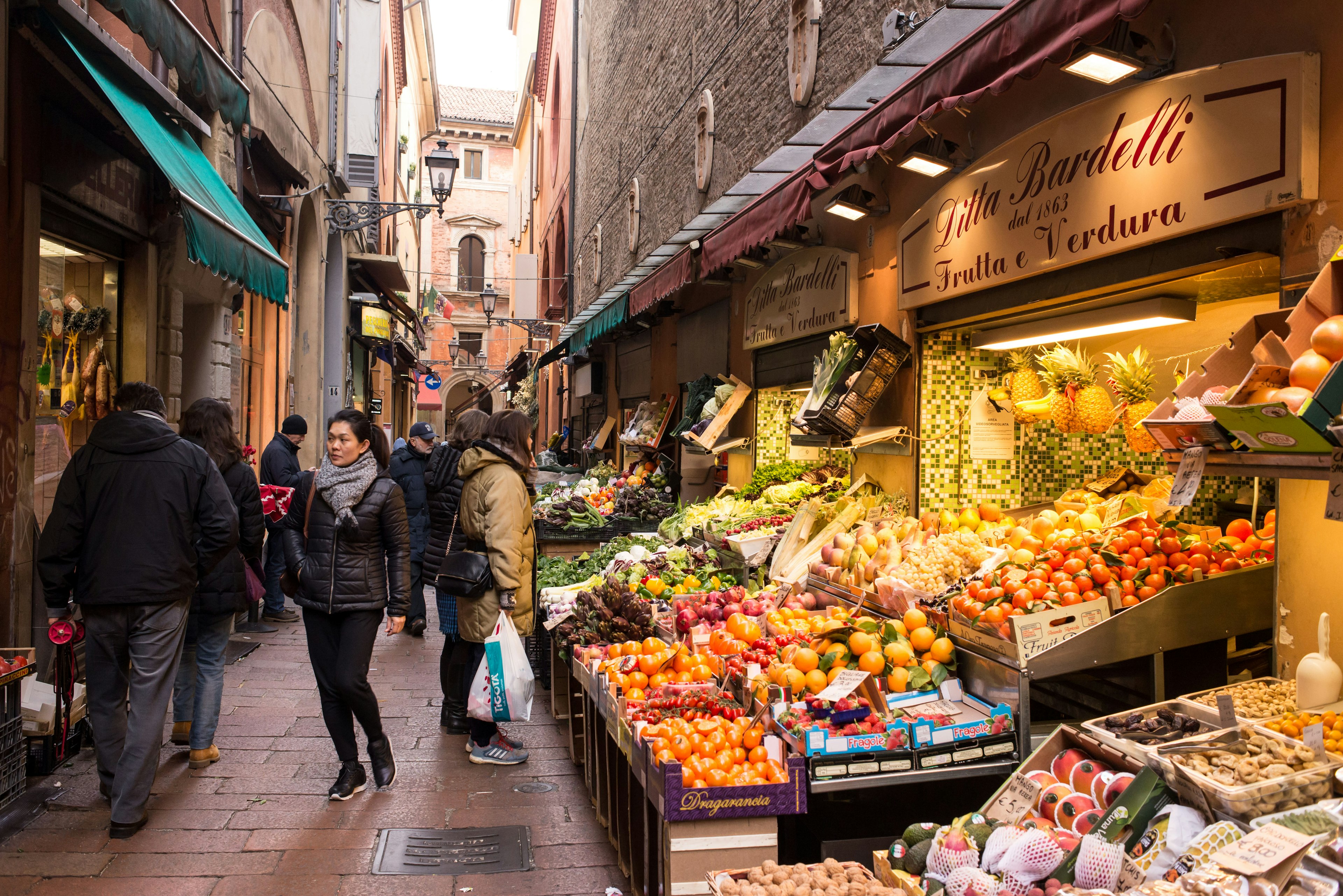 People walking in Via Pescherie Vecchie, a famous alley full of traditional stores and food stalls in the characteristic medieval city centre of Bologna, Italy.