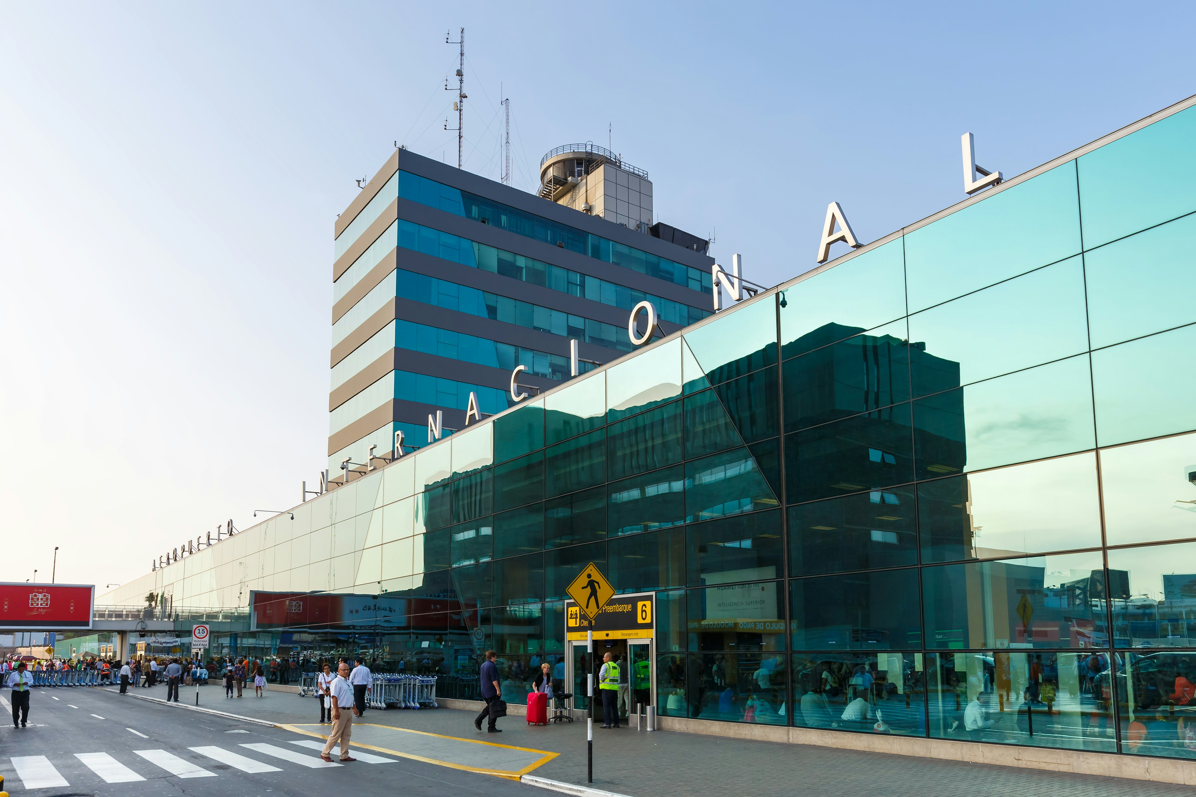 People walking outside of the glass-fronted international terminal at the Lima airport in Peru