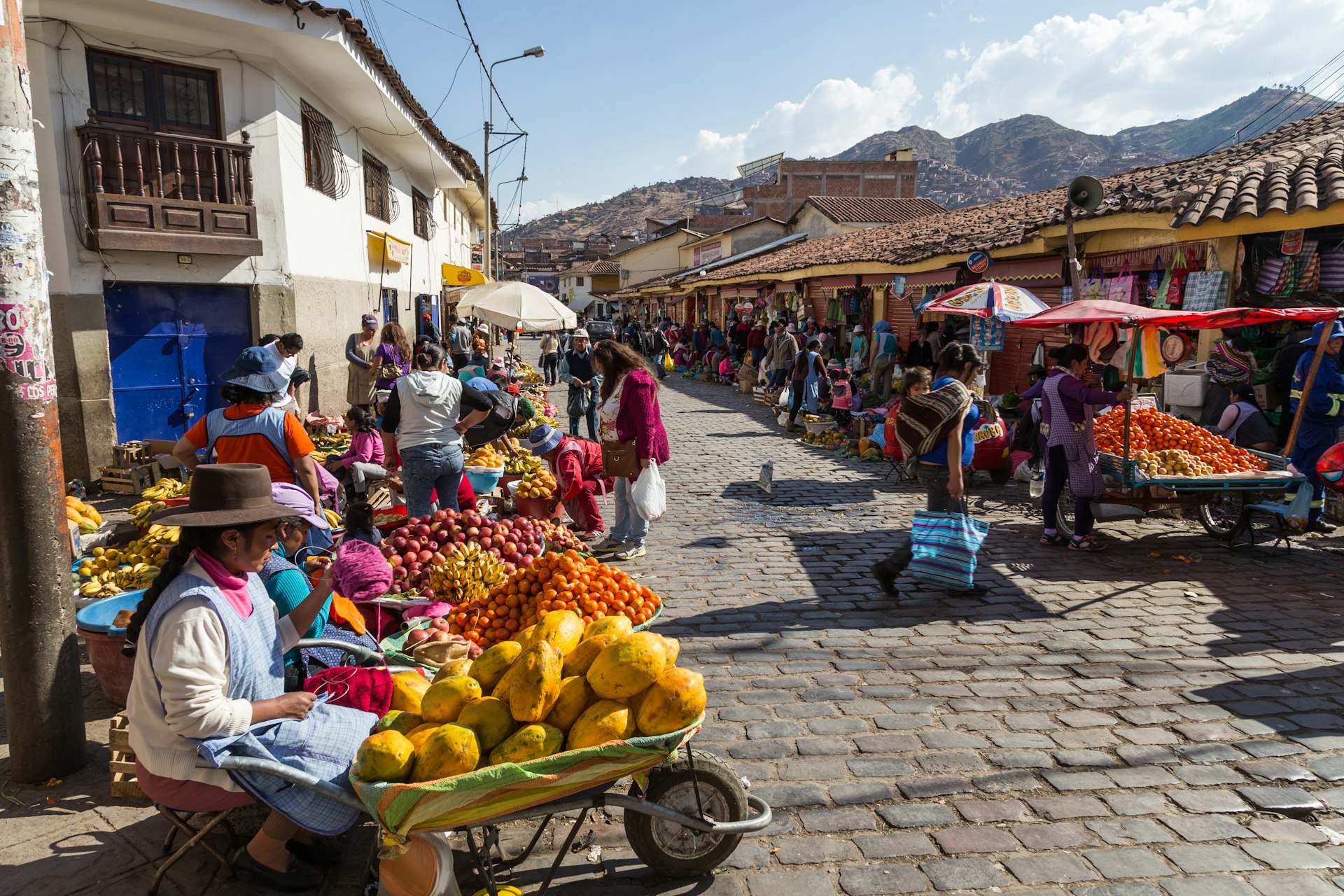 People selling and buying fruits at a market in the streets of Cuzco