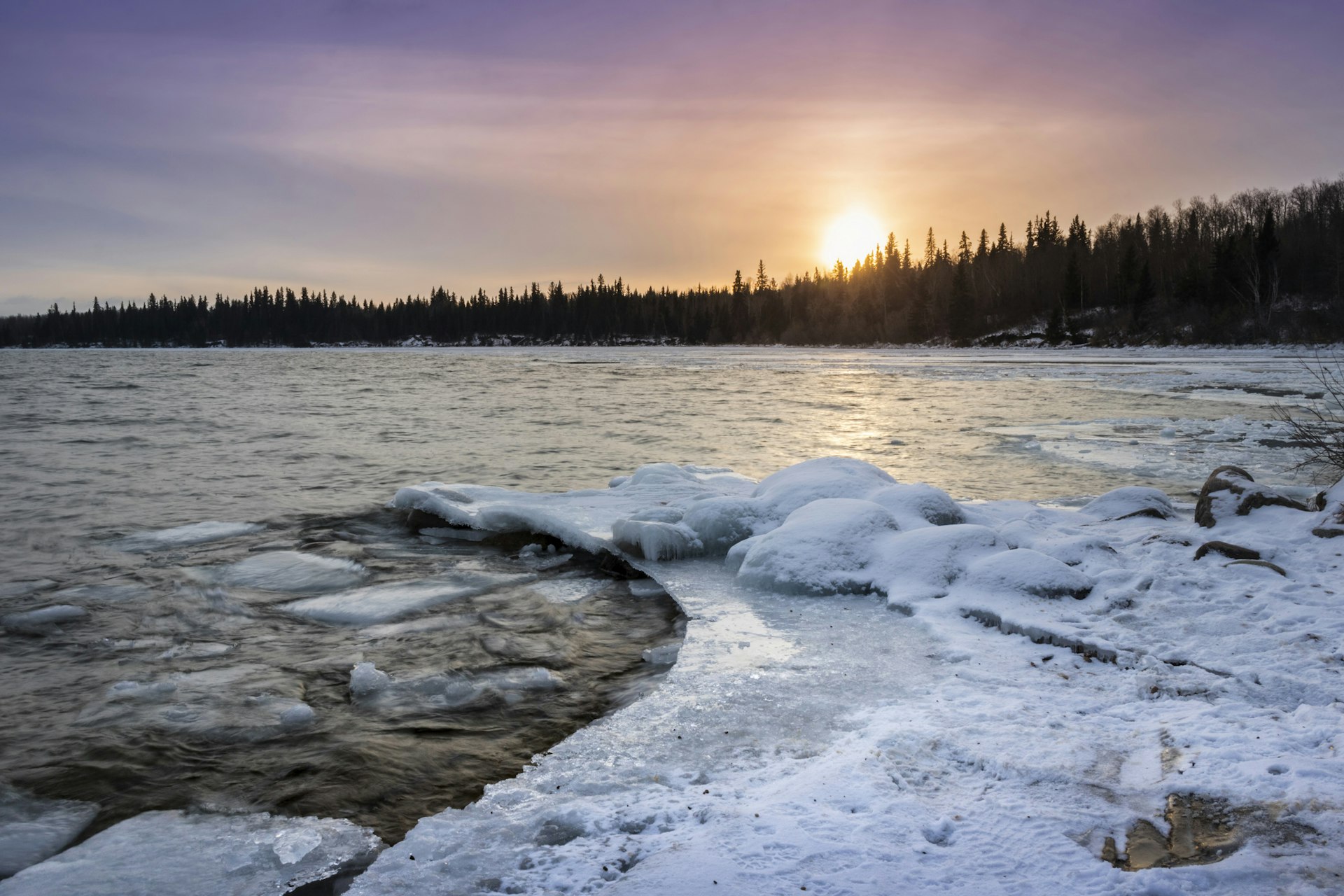 Beautiful vibrant sunset scene over the Provincial Park at Cold Lake, Alberta which has a snow-covered shoreline